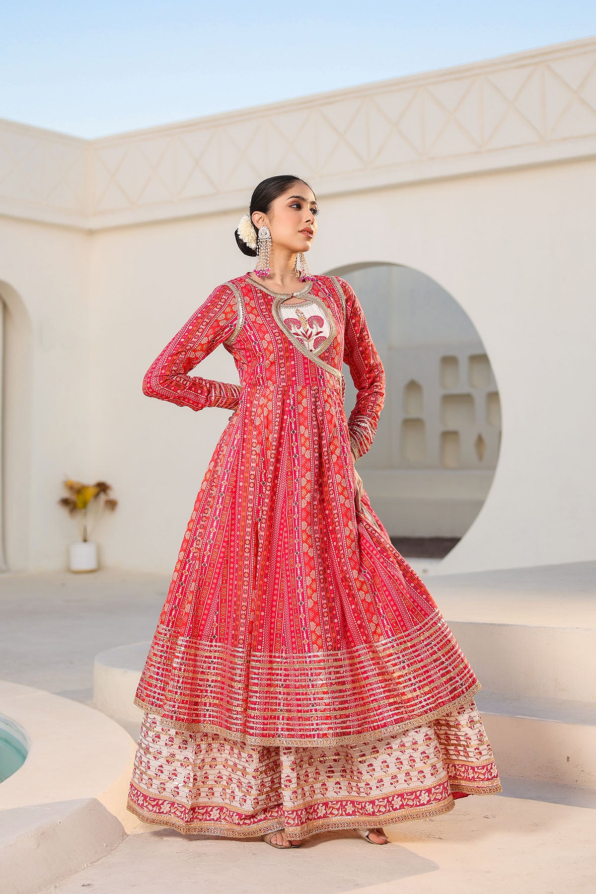 Woman in a red and white traditional outfit standing in front of a white architectural structure.