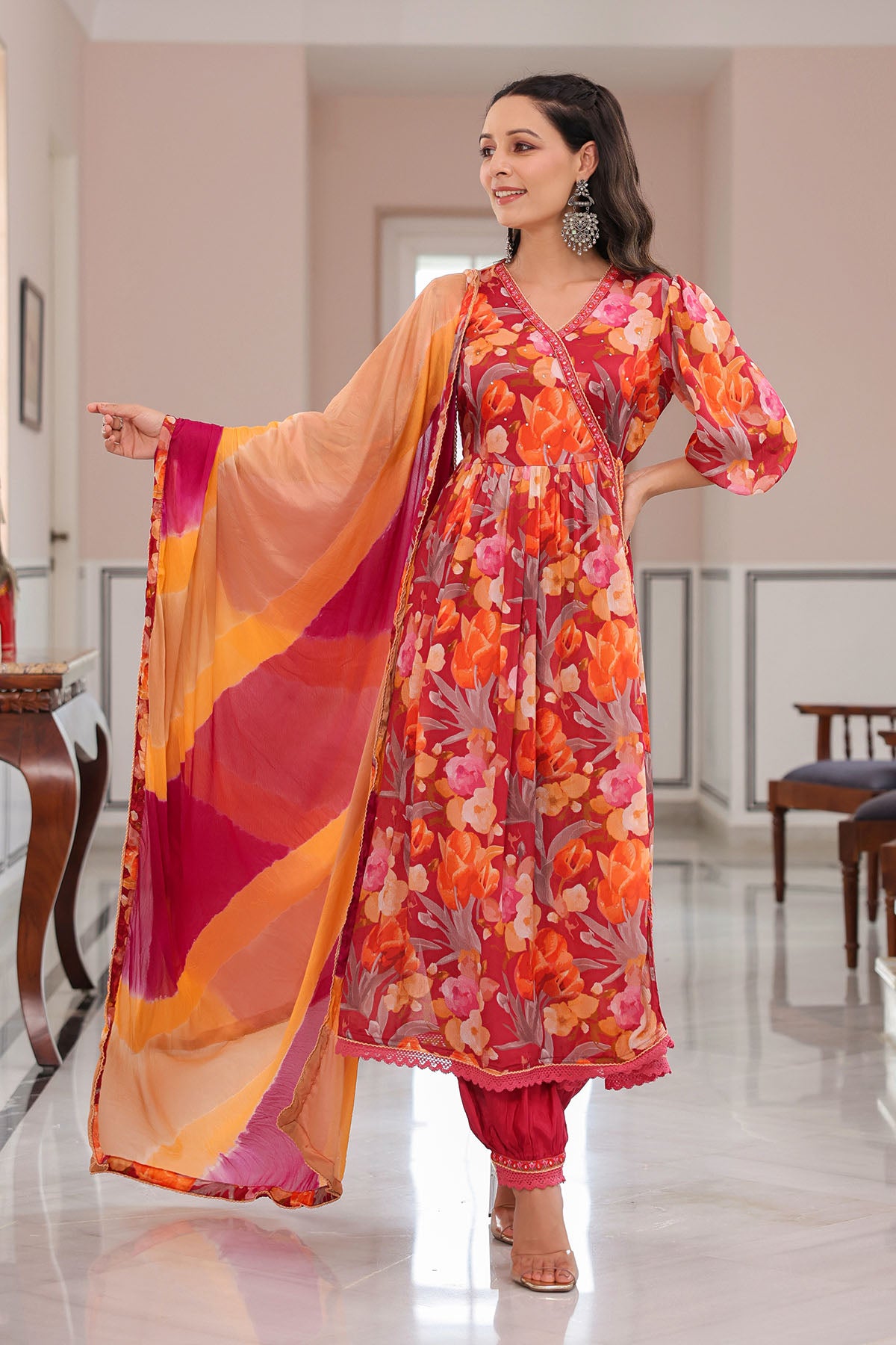 Woman in a colorful floral dress with a matching dupatta in a well-lit room.
