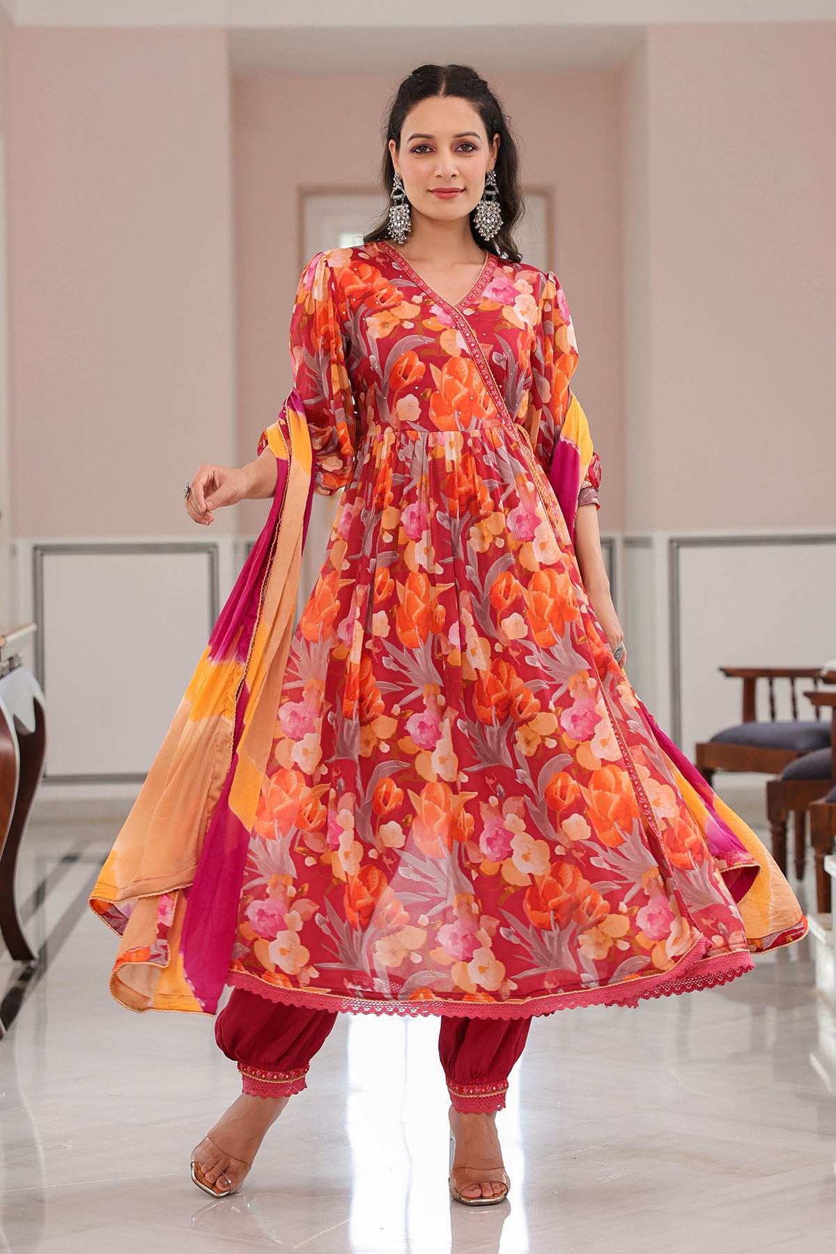 Woman wearing a colorful floral dress with a matching dupatta in an indoor setting