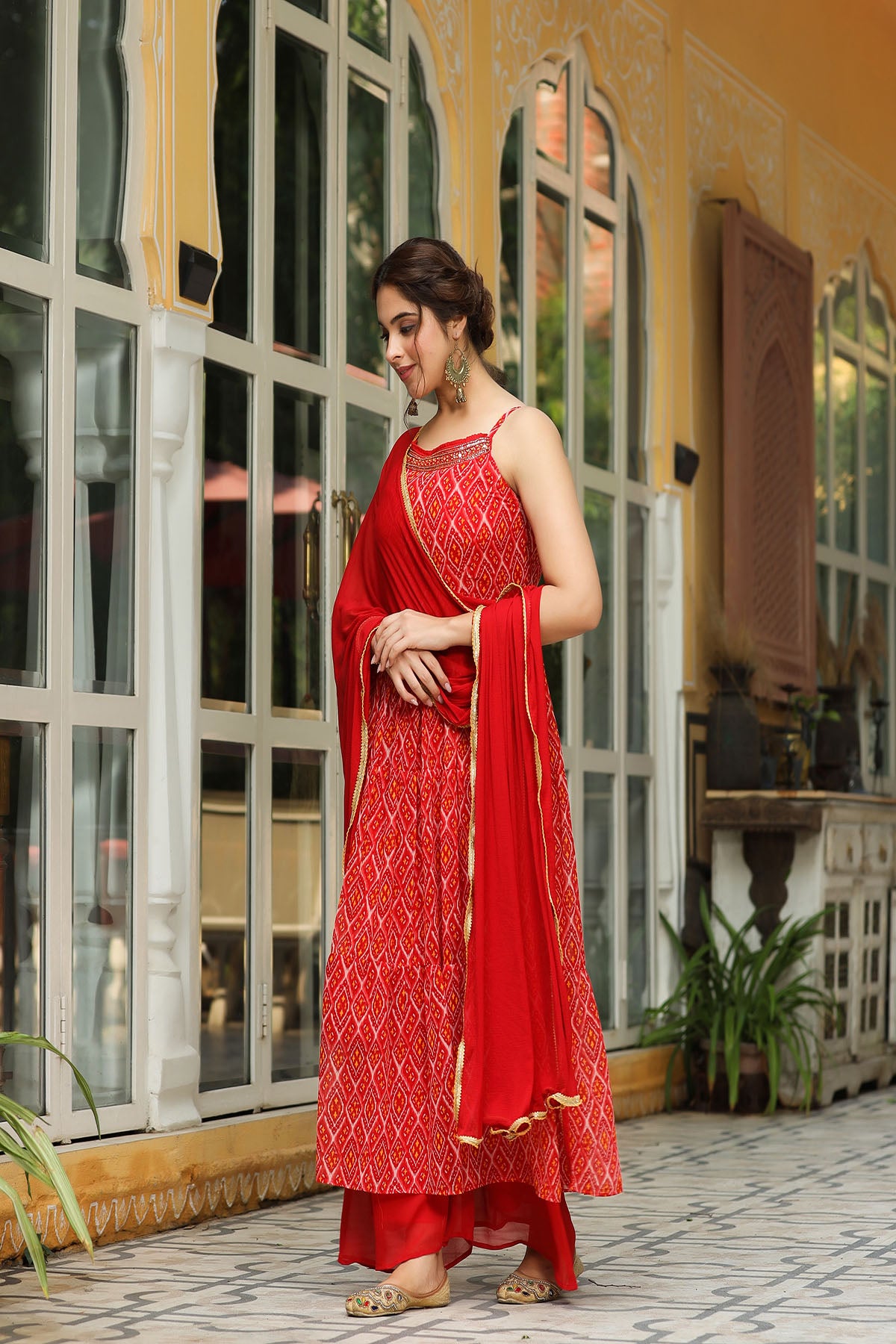 Woman in a red traditional outfit standing in front of a glass door.