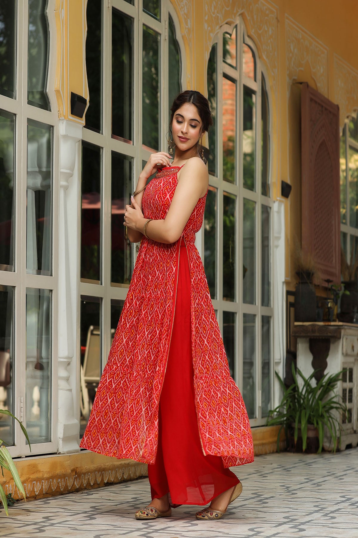 Woman in a red dress standing in front of a decorative building entrance.
