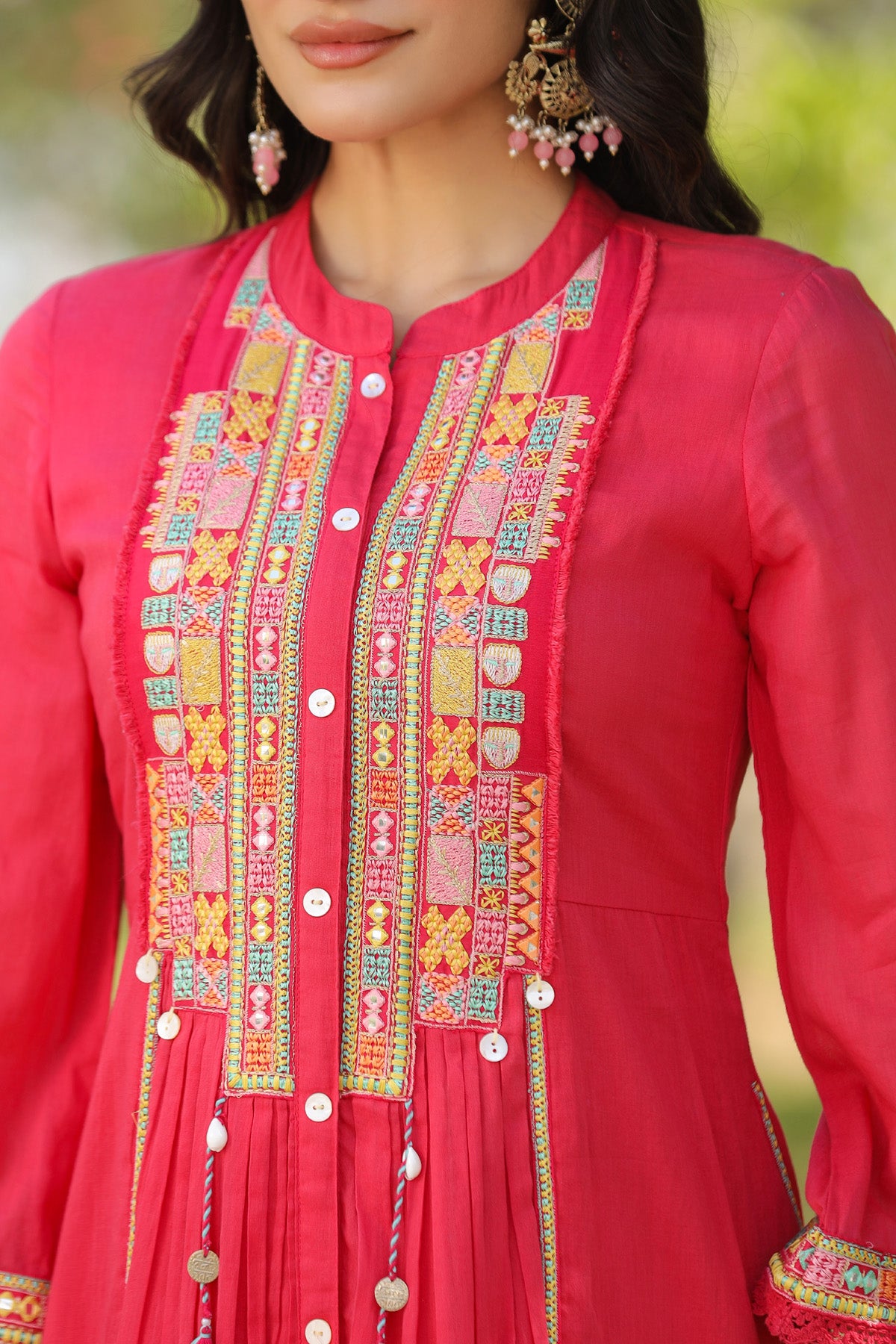 Close-up of a red traditional outfit with intricate embroidery and buttons.