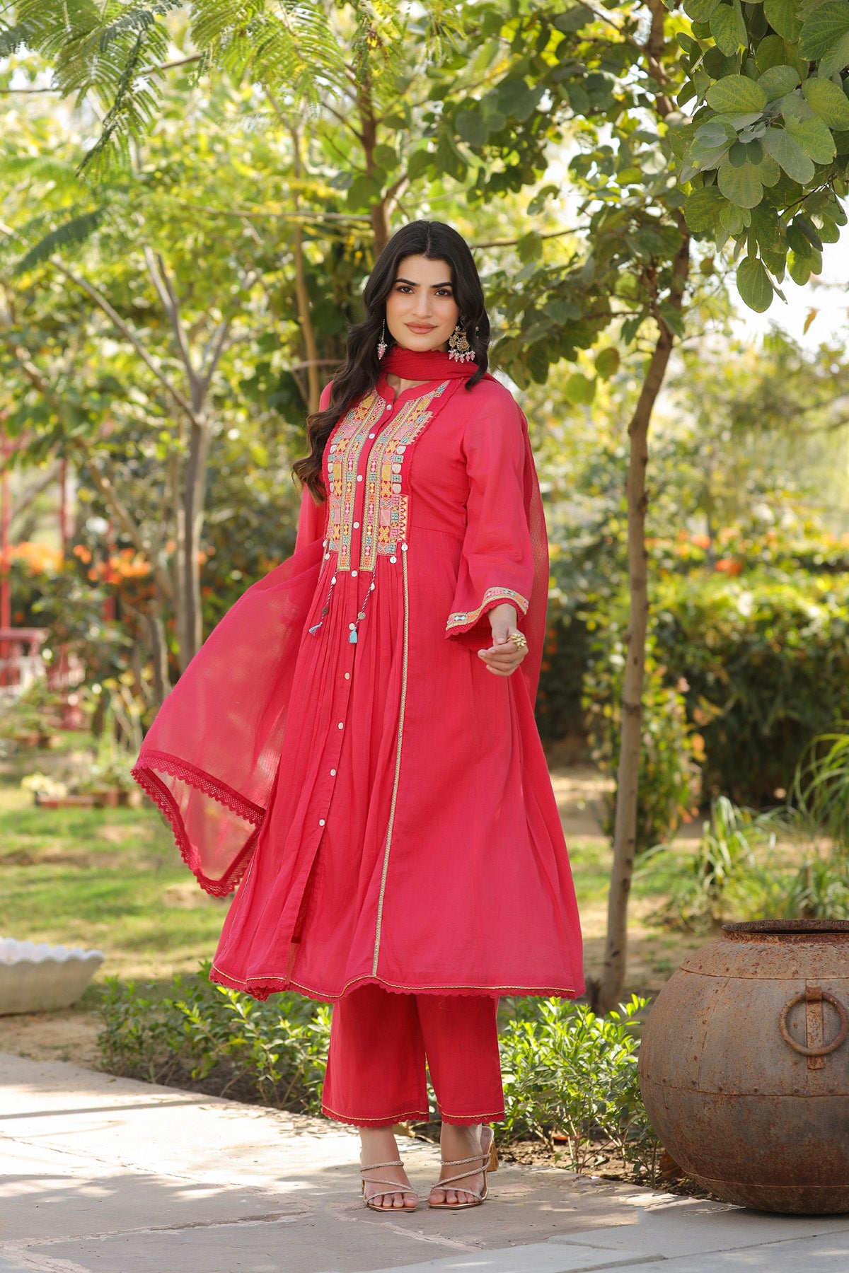Woman in a bright pink traditional outfit standing in a garden.