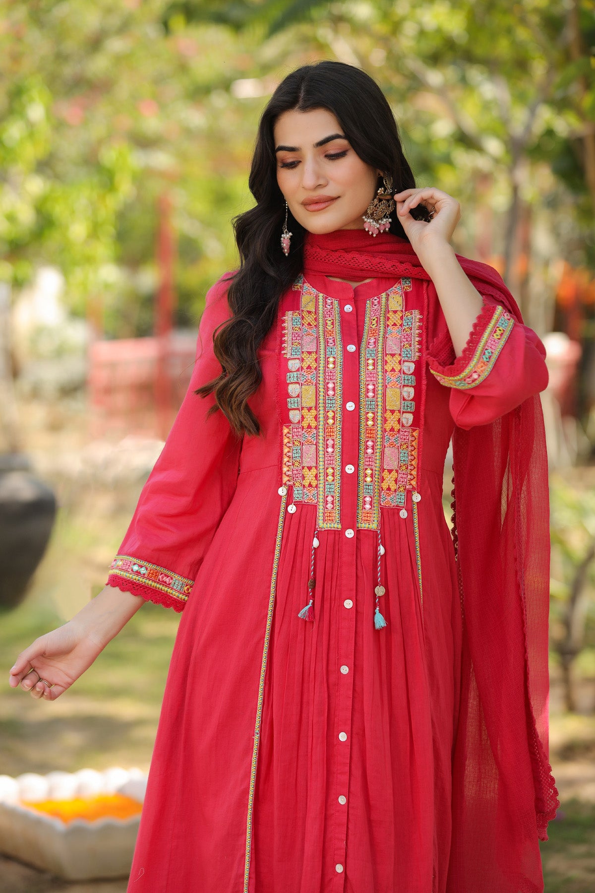 Woman wearing a red embroidered traditional outfit with a blurred natural background