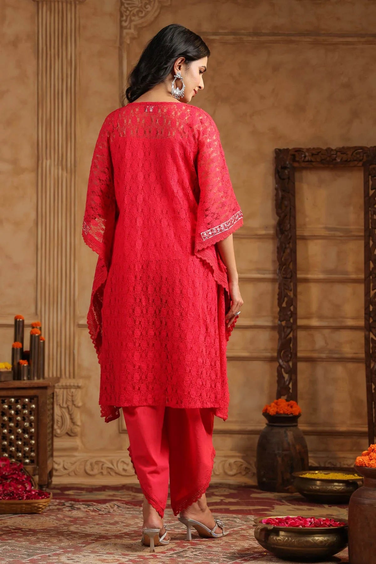 Woman in a red traditional outfit standing in a decorated room with decorative elements.