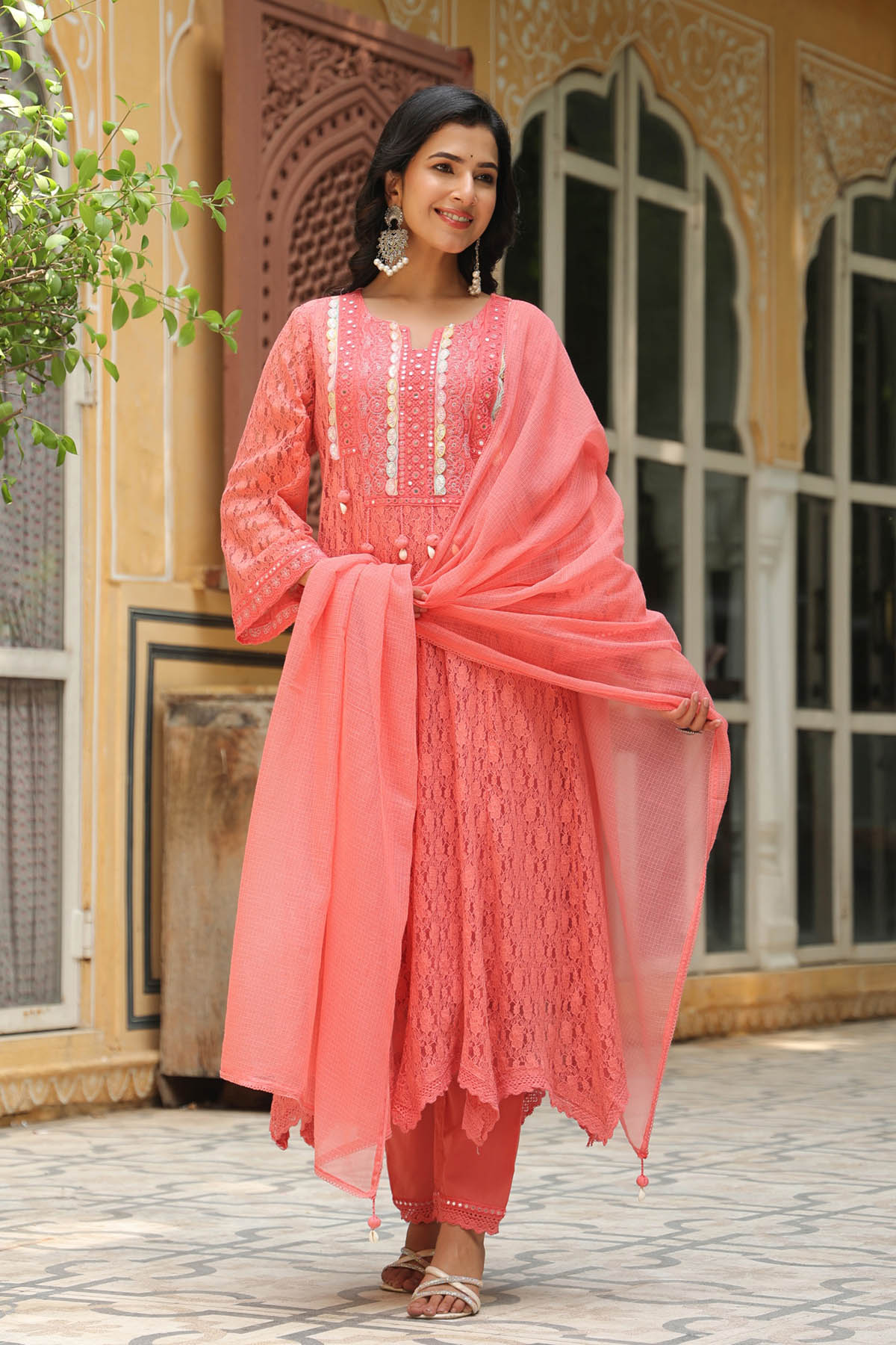 Woman in a pink traditional outfit standing in front of an ornate building.