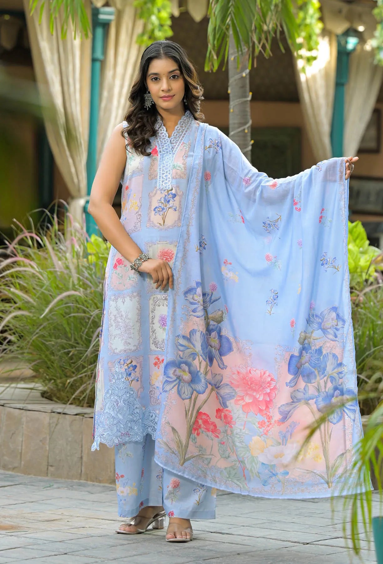 Woman wearing a light blue floral dress with a matching dupatta in an outdoor setting.