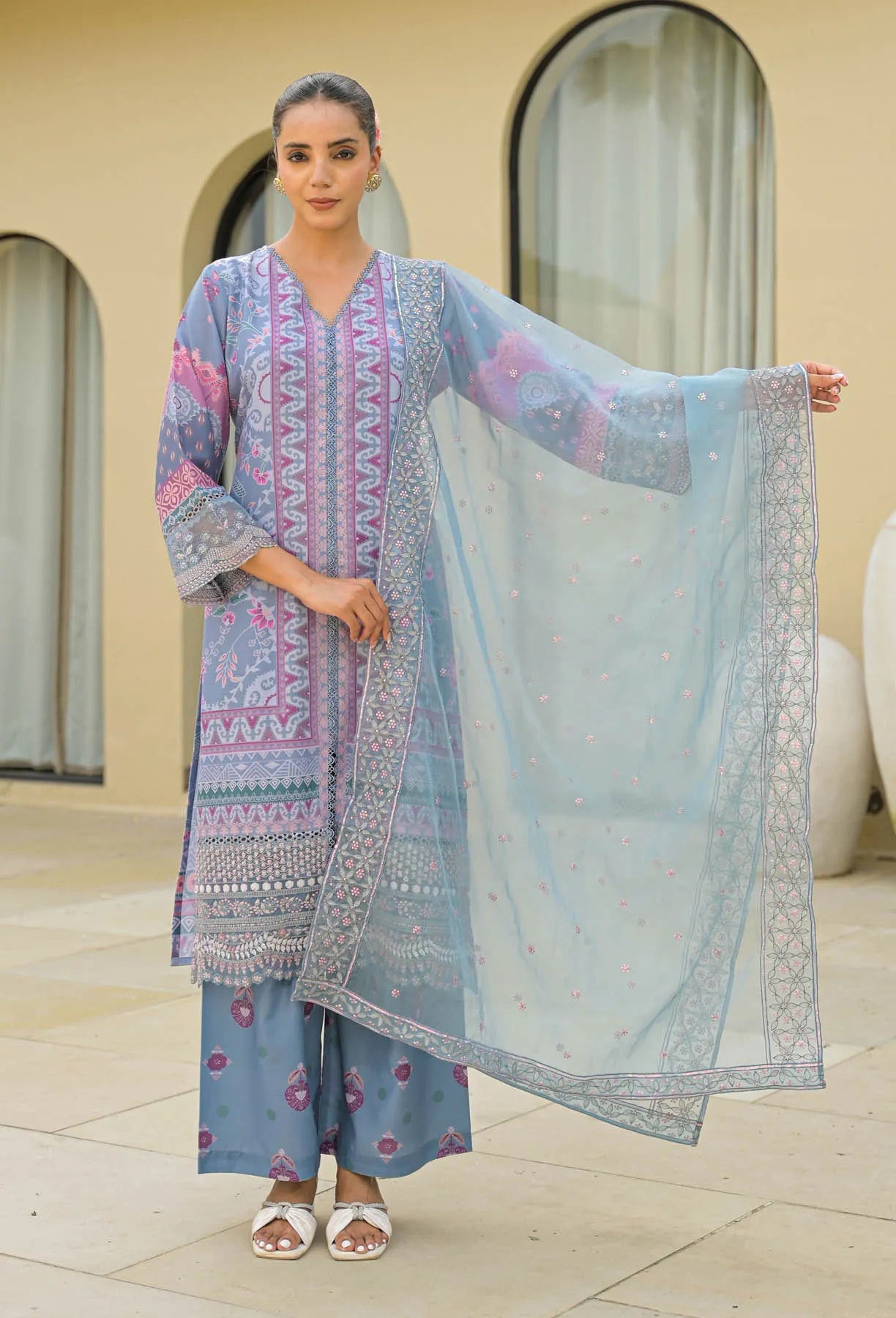 Woman wearing a traditional outfit with a matching dupatta in an outdoor setting.