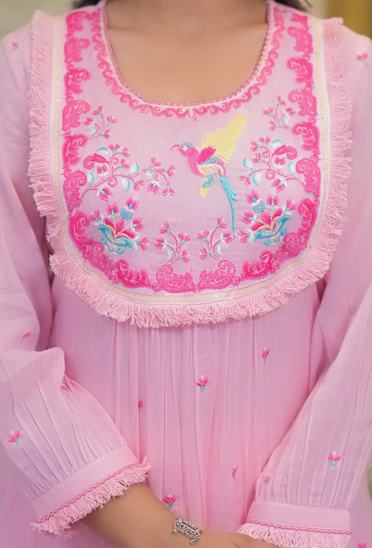 Pink apron with embroidered design on a blurred background