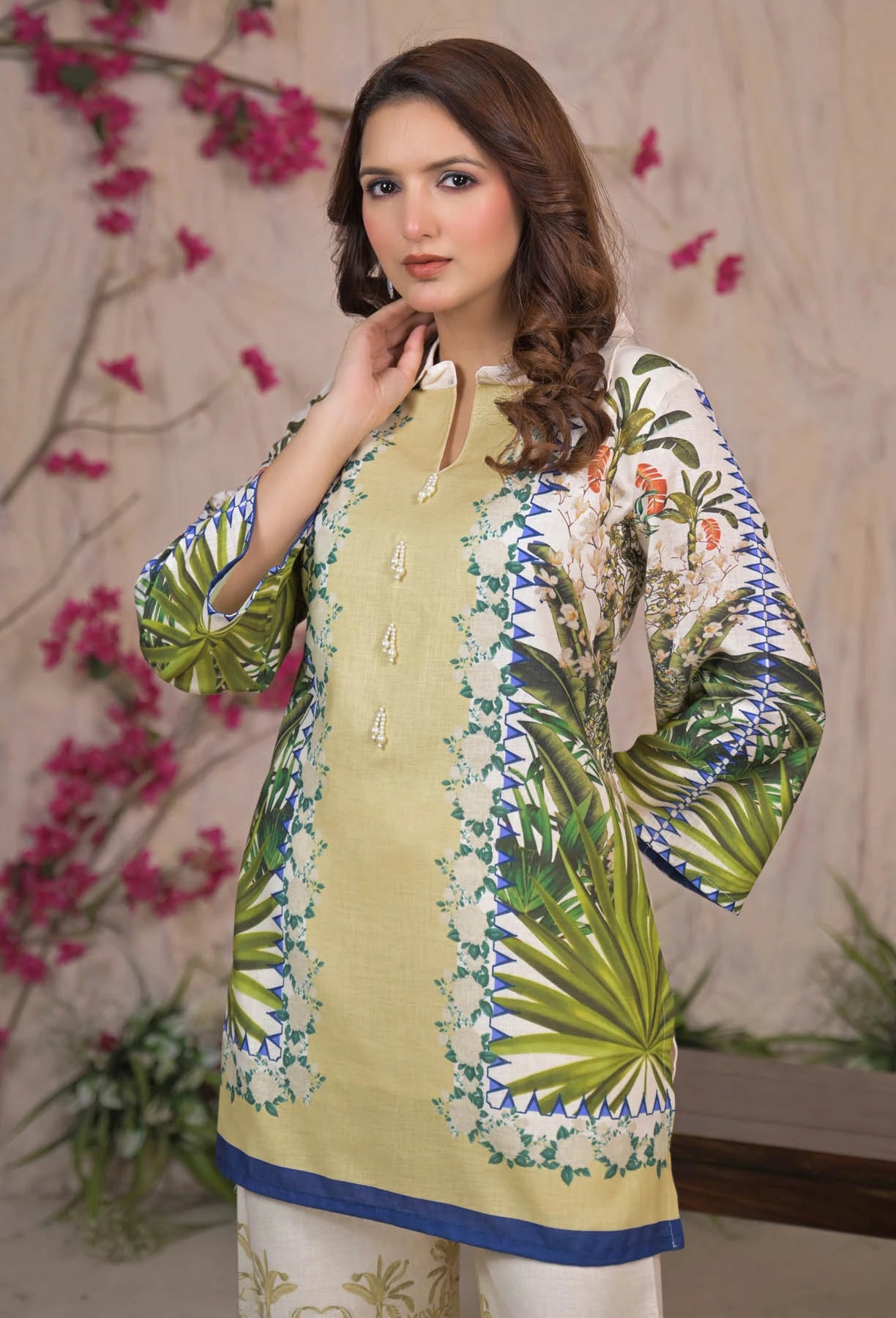 Woman wearing a green and white floral embroidered shirt with a beige background