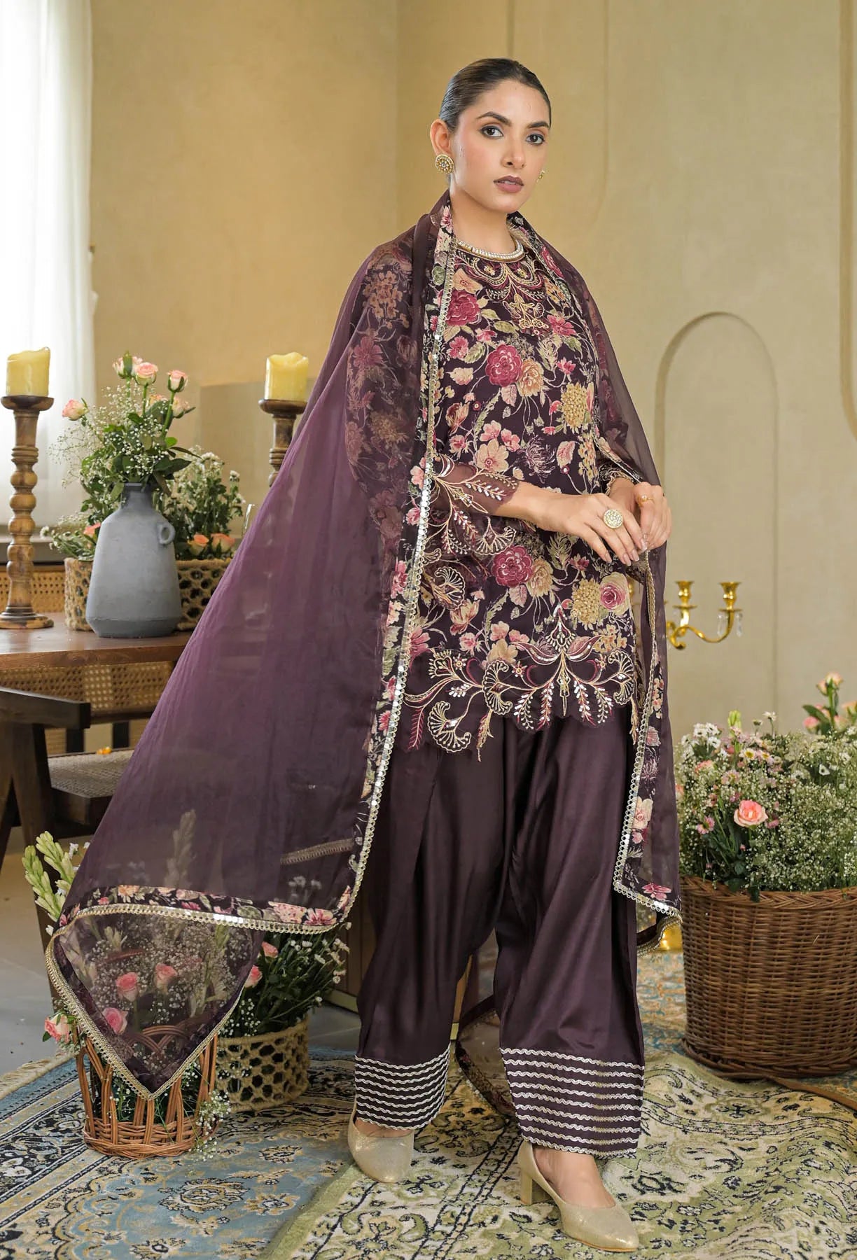 Woman in traditional outfit with floral patterns in a decorated room.