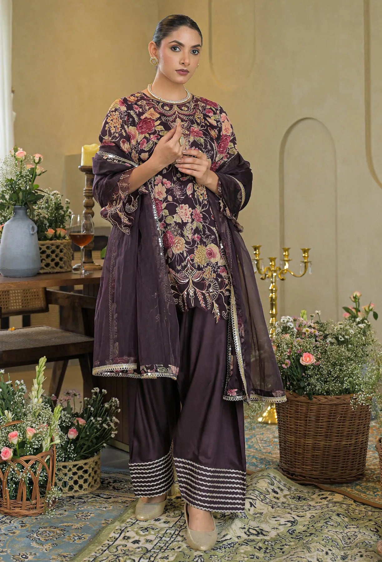Woman in traditional outfit with floral patterns in a decorated room.
