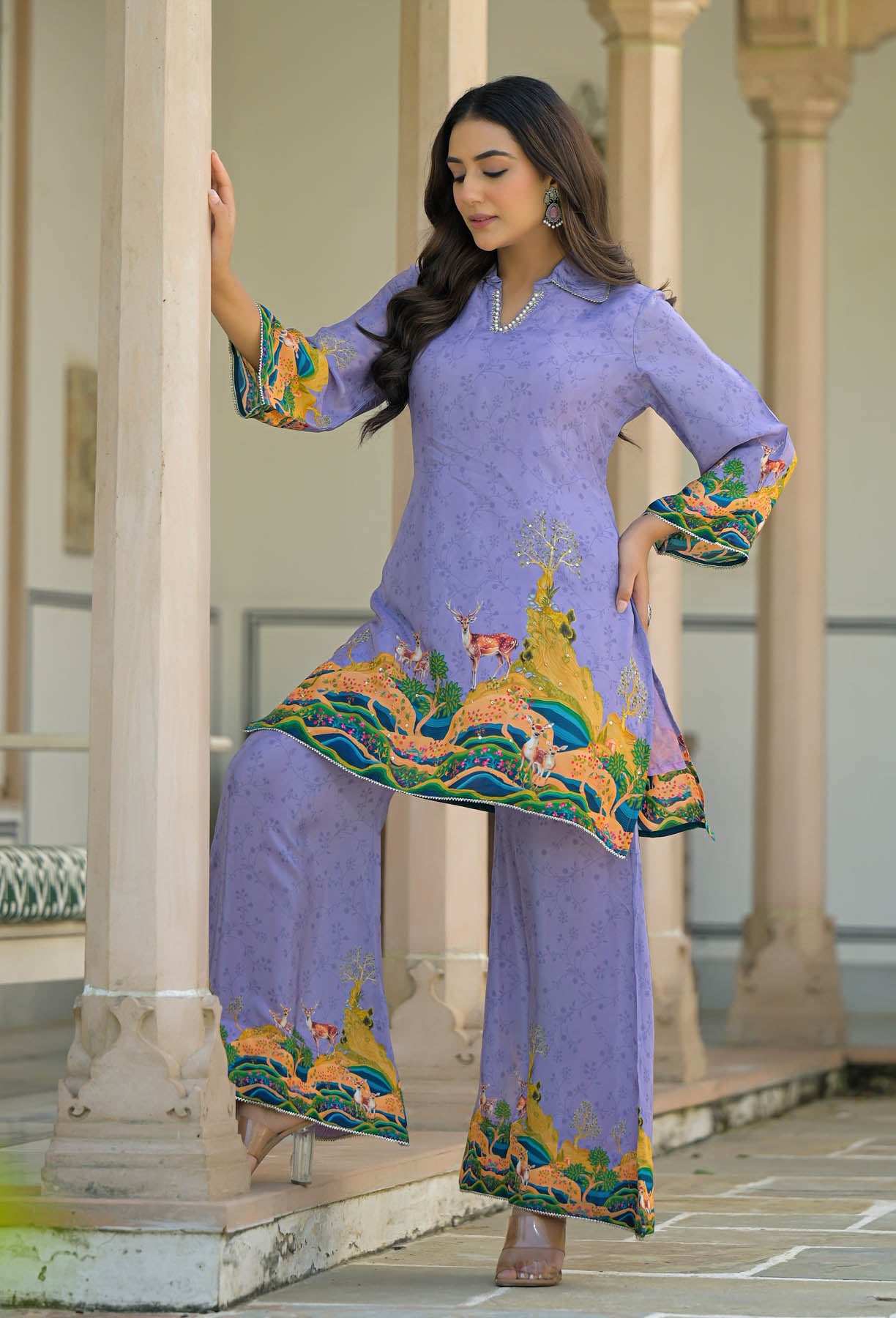 Woman in a traditional outfit with floral patterns standing in an architectural setting.