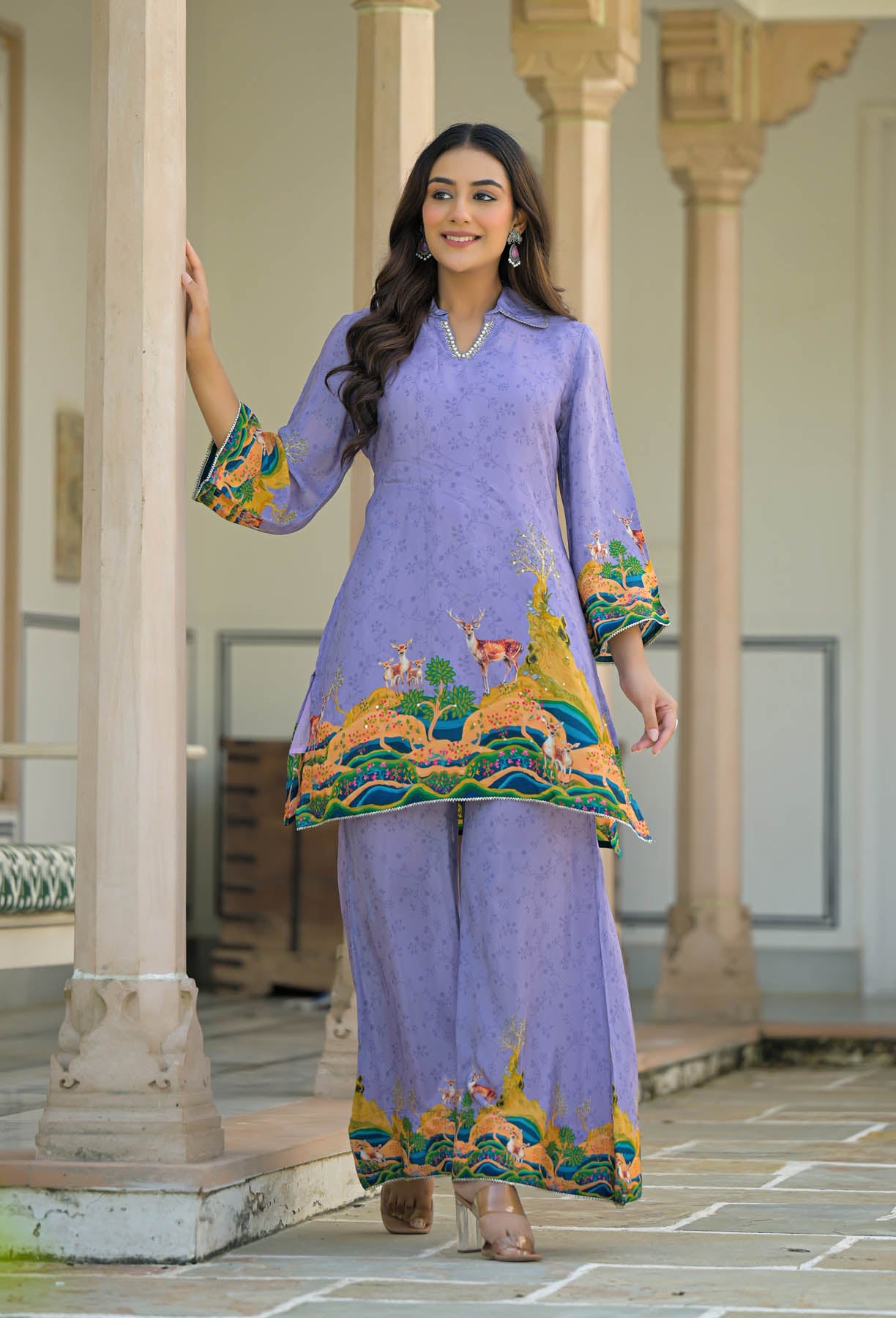 Woman in a lavender traditional outfit with colorful embroidery standing in an outdoor setting.