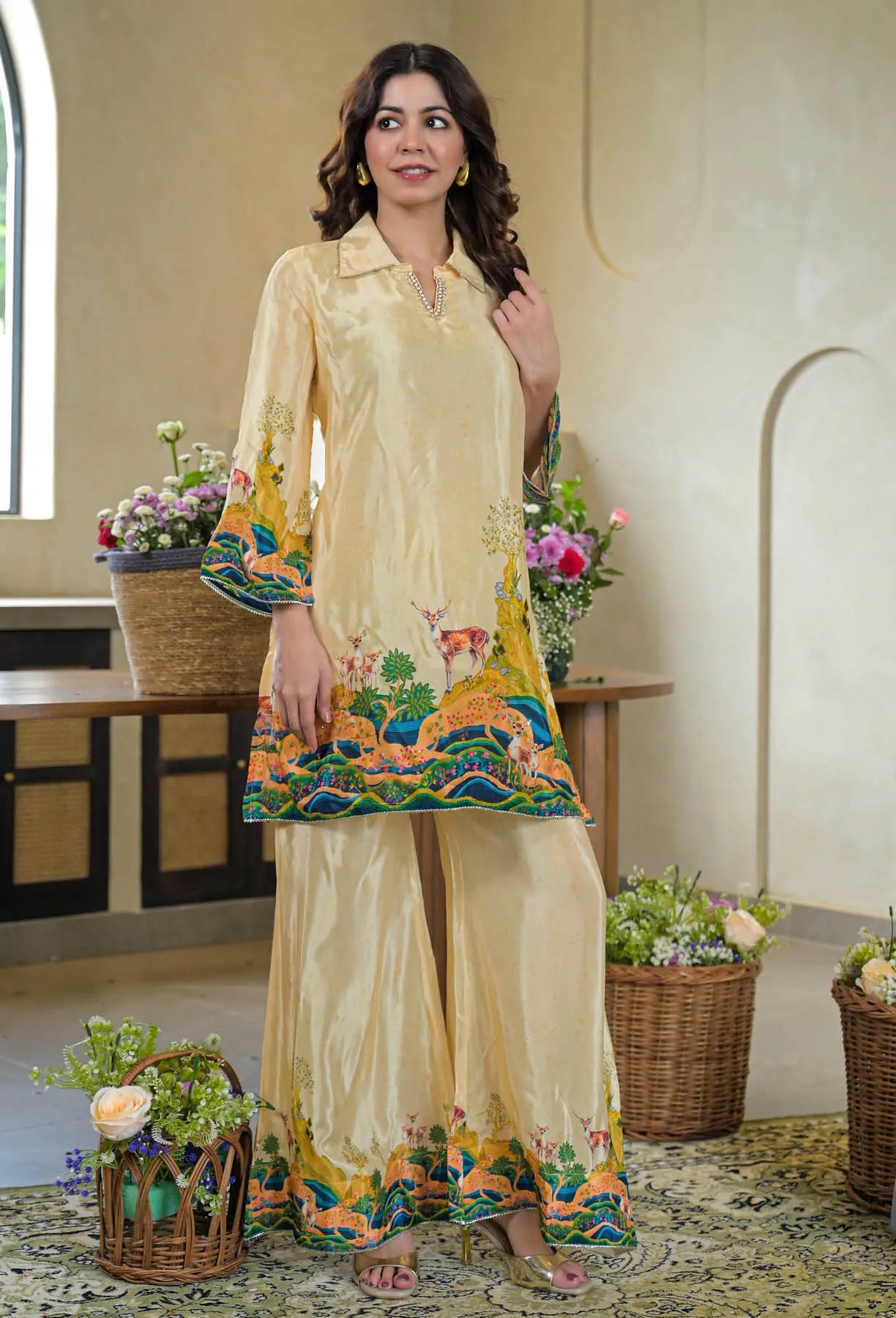 Woman wearing a cream-colored embroidered outfit in an indoor setting with decorative elements.