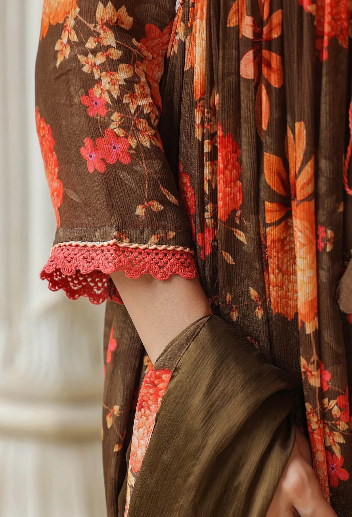 Close-up of a person wearing a floral dress with red accents and lace details.