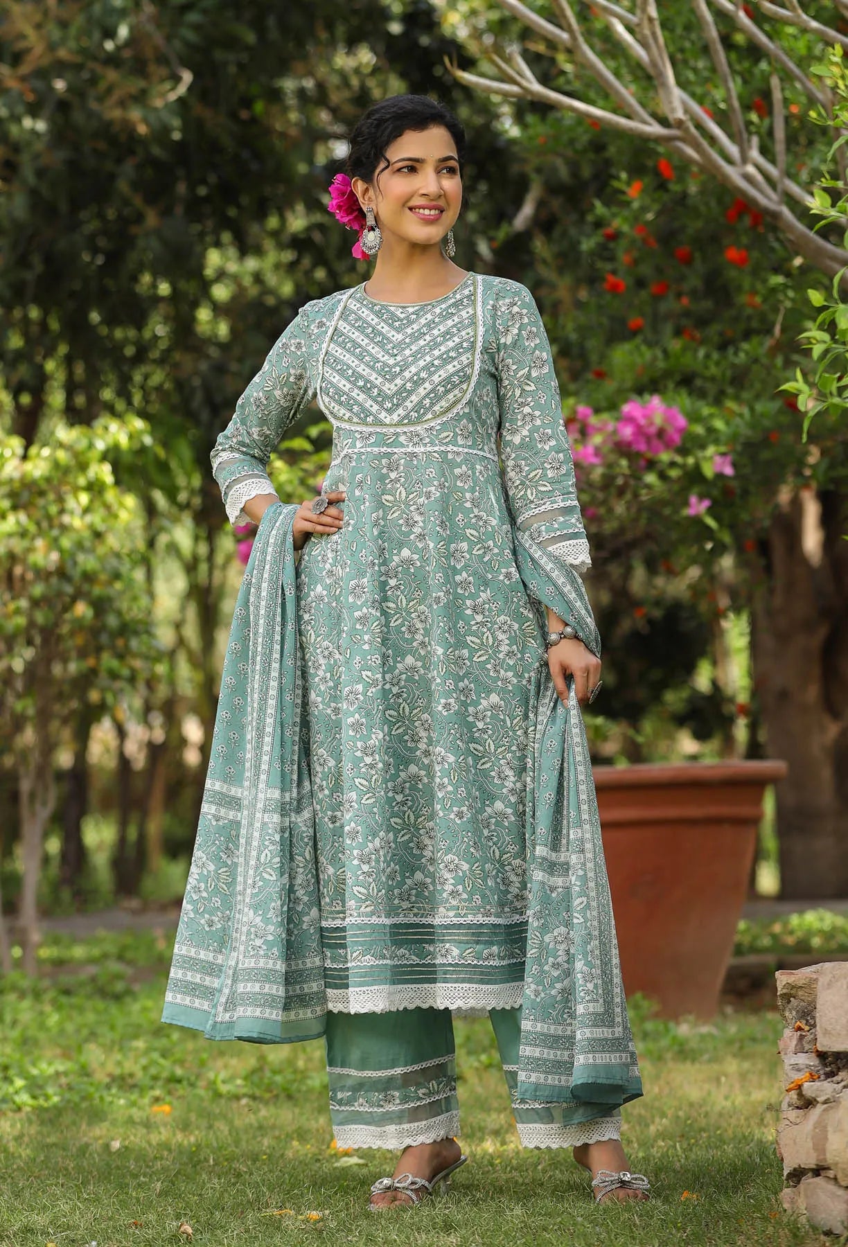 Woman wearing a green and white traditional outfit in a garden setting