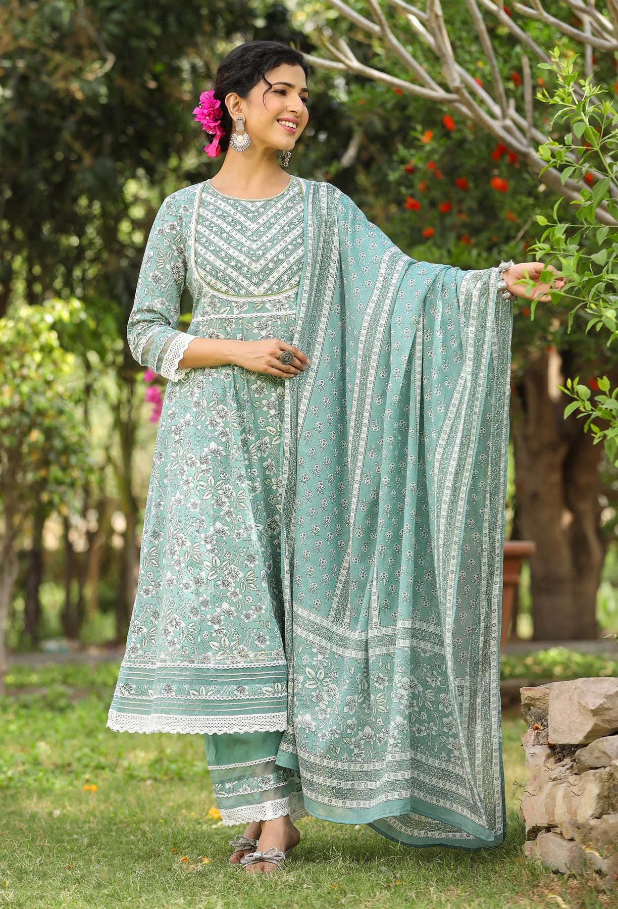 Woman in a light green traditional outfit with a matching dupatta, standing outdoors.