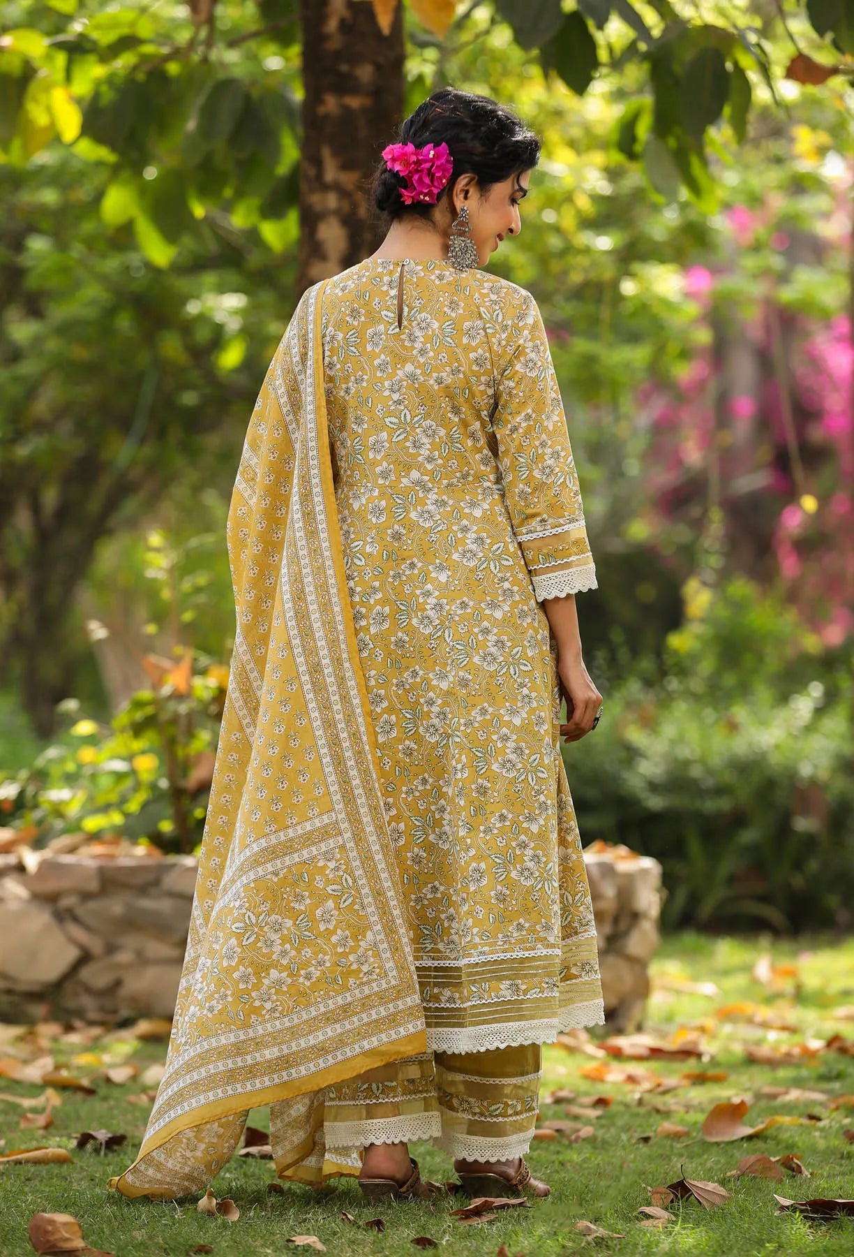 Woman in a yellow traditional outfit standing in a garden