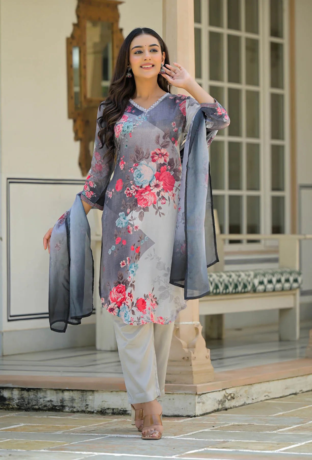 Woman wearing a floral outfit with a gray jacket in an outdoor setting.