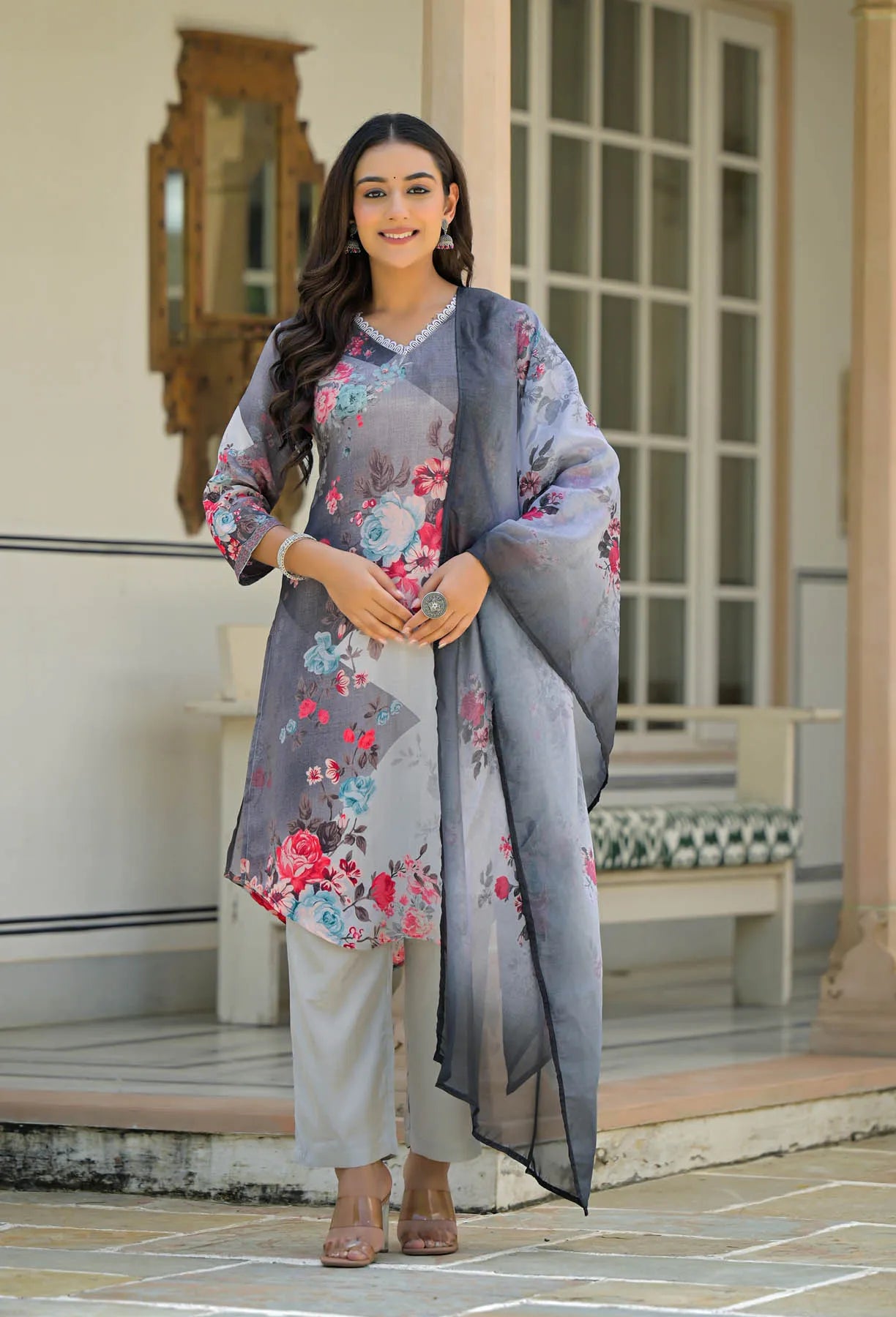Woman wearing a floral dress with a gray dupatta in an outdoor setting