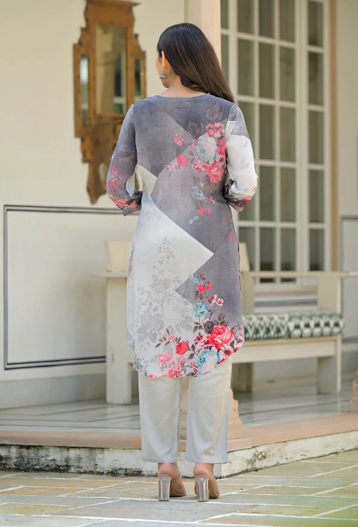 Woman wearing a gray floral outfit standing in an outdoor setting.