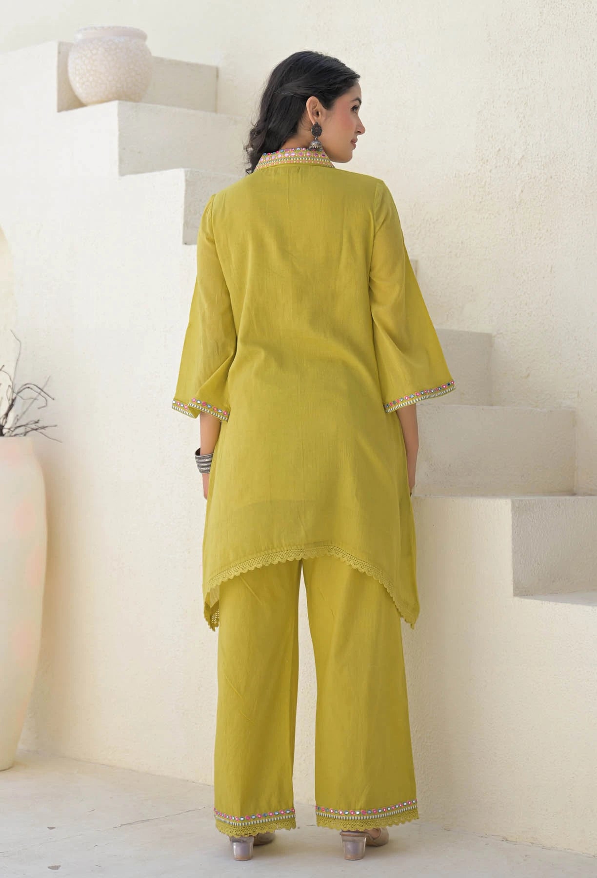 Woman wearing a yellow traditional outfit standing on a white staircase.