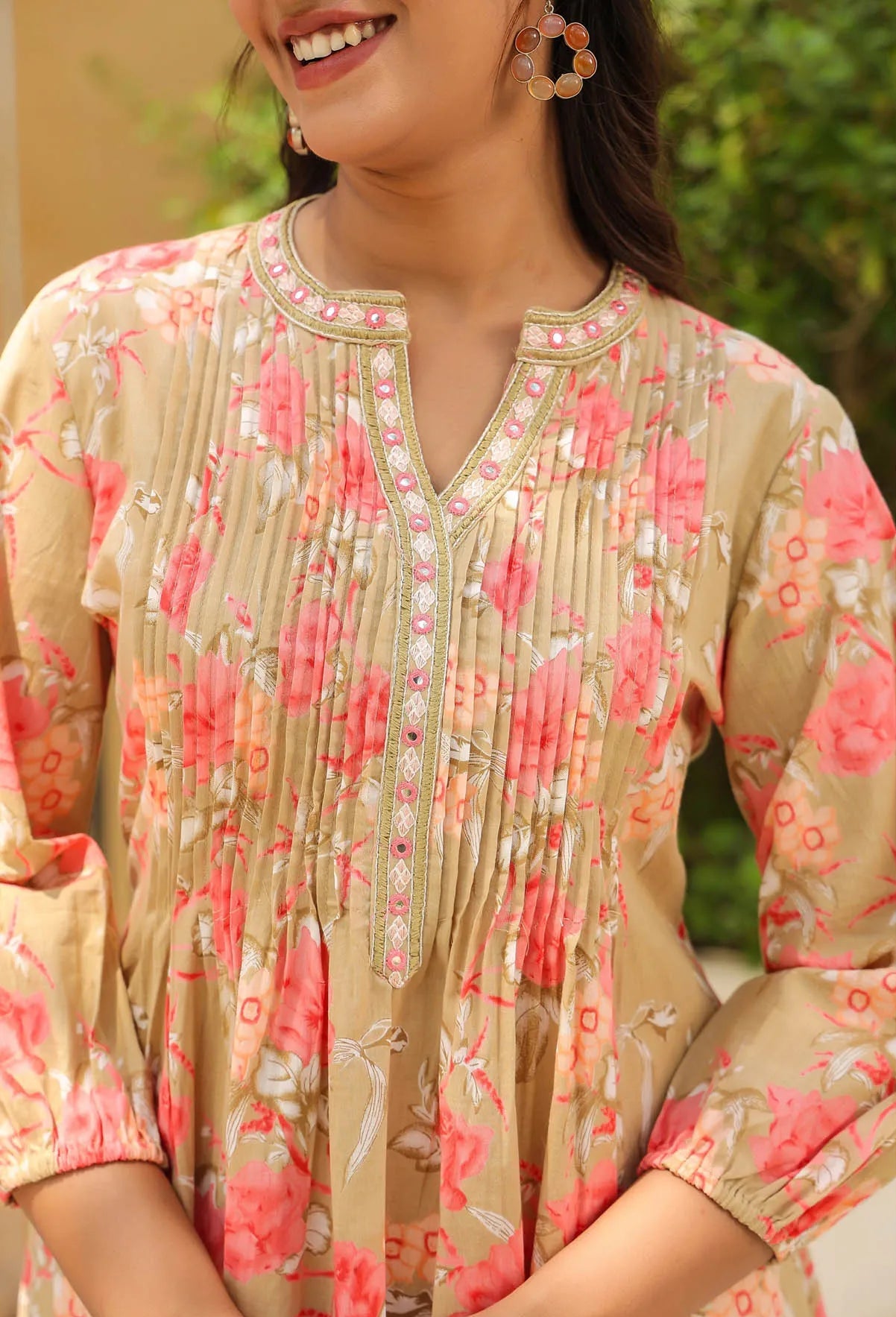 Woman wearing a floral patterned kurta with a blurred green background