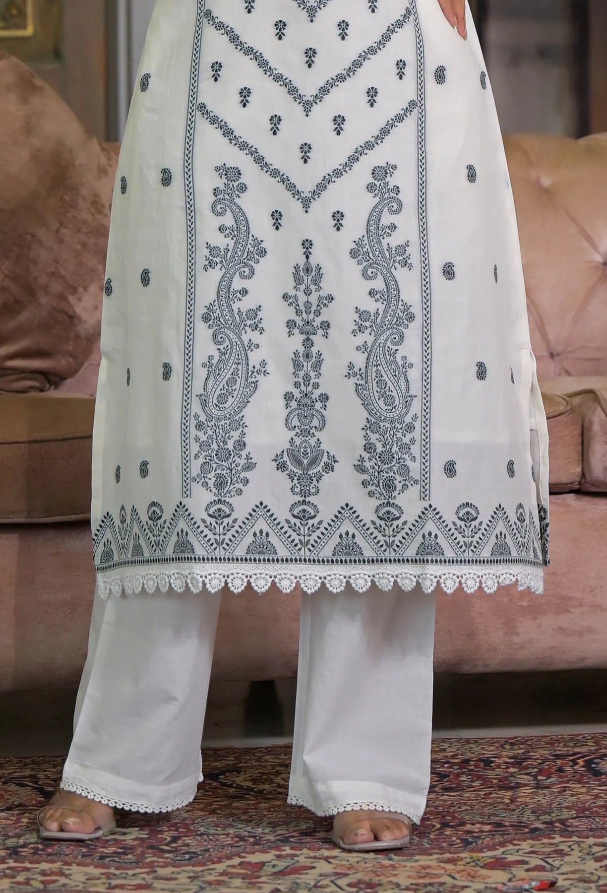 White outfit with black embroidery on a patterned rug