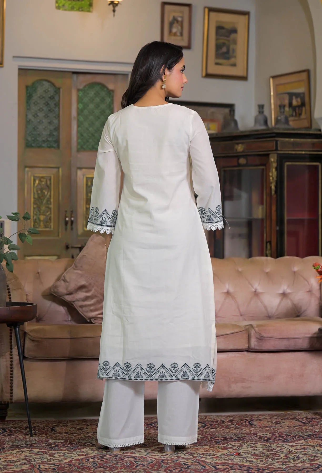 Woman in a white traditional outfit standing in a living room.