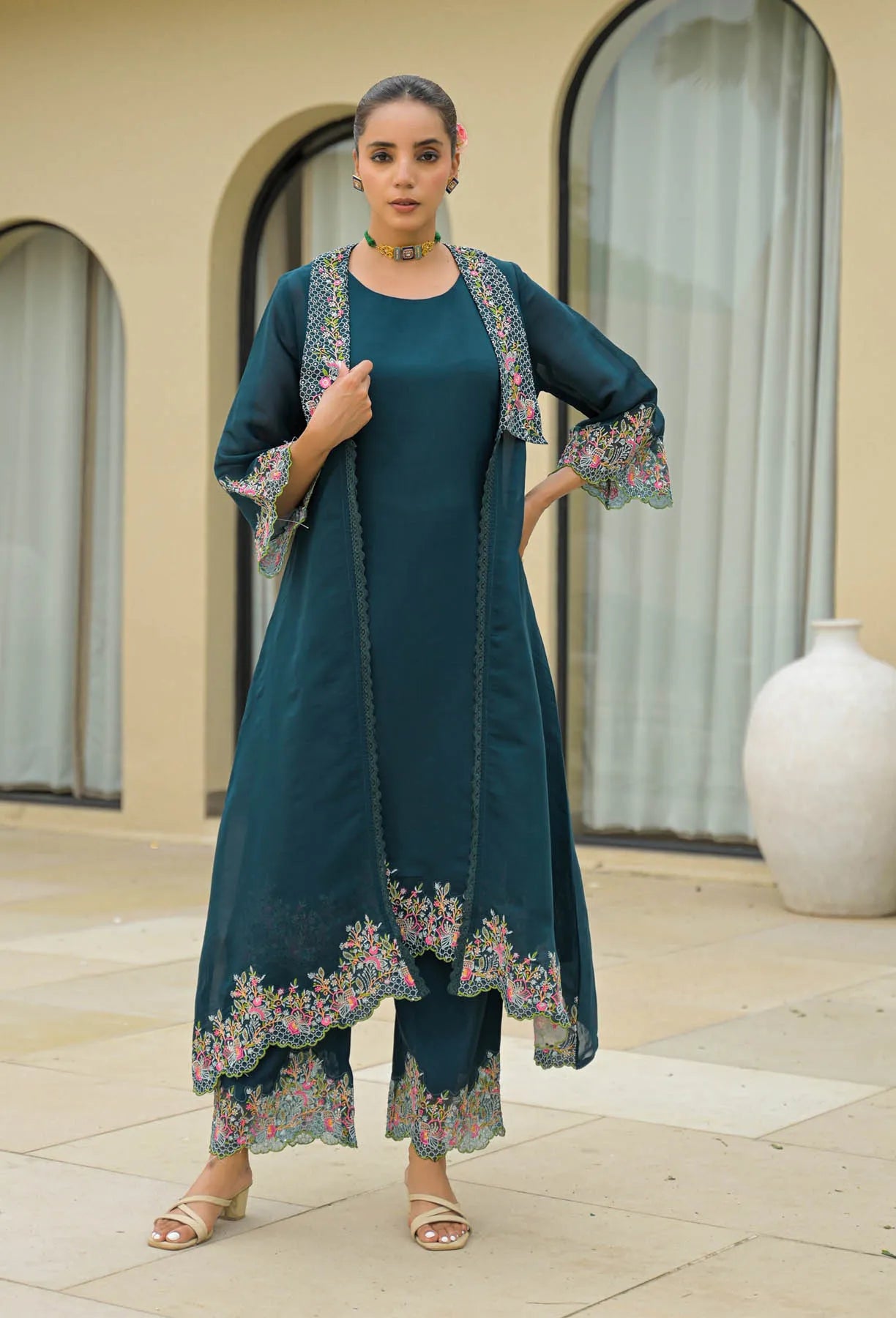 Woman wearing a teal outfit with floral embroidery in an outdoor setting
