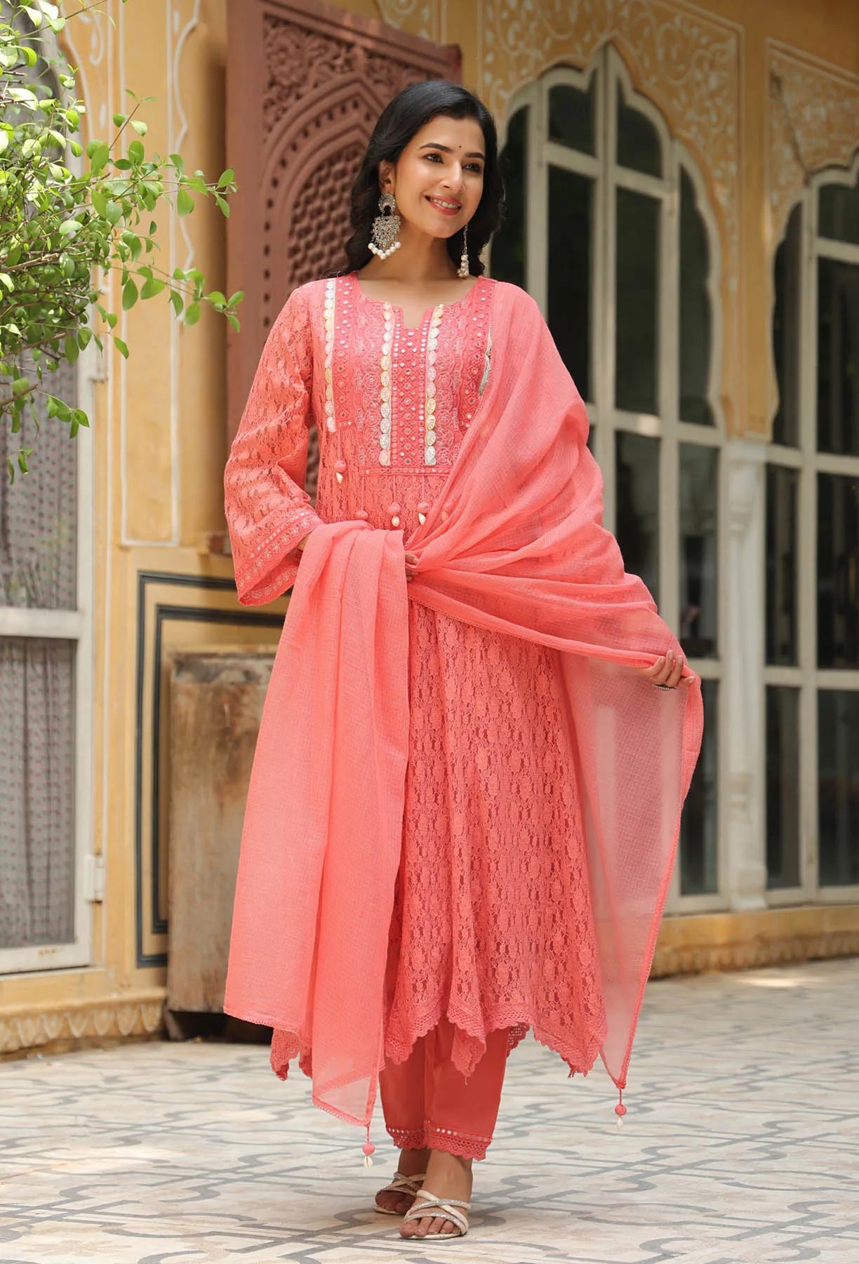 Woman in a pink traditional outfit standing in front of an architectural background