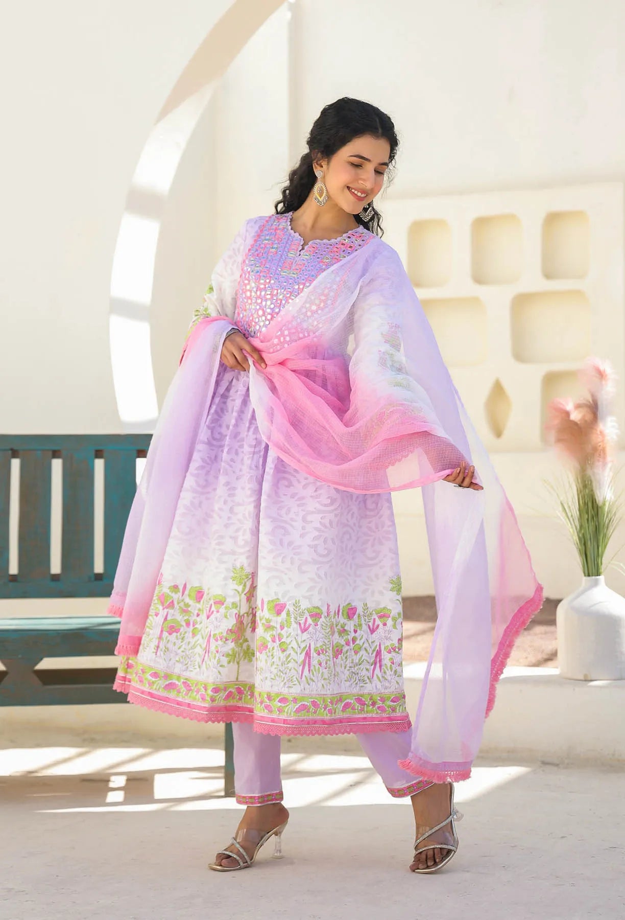 Woman wearing a traditional outfit with a pink dupatta in a bright room.