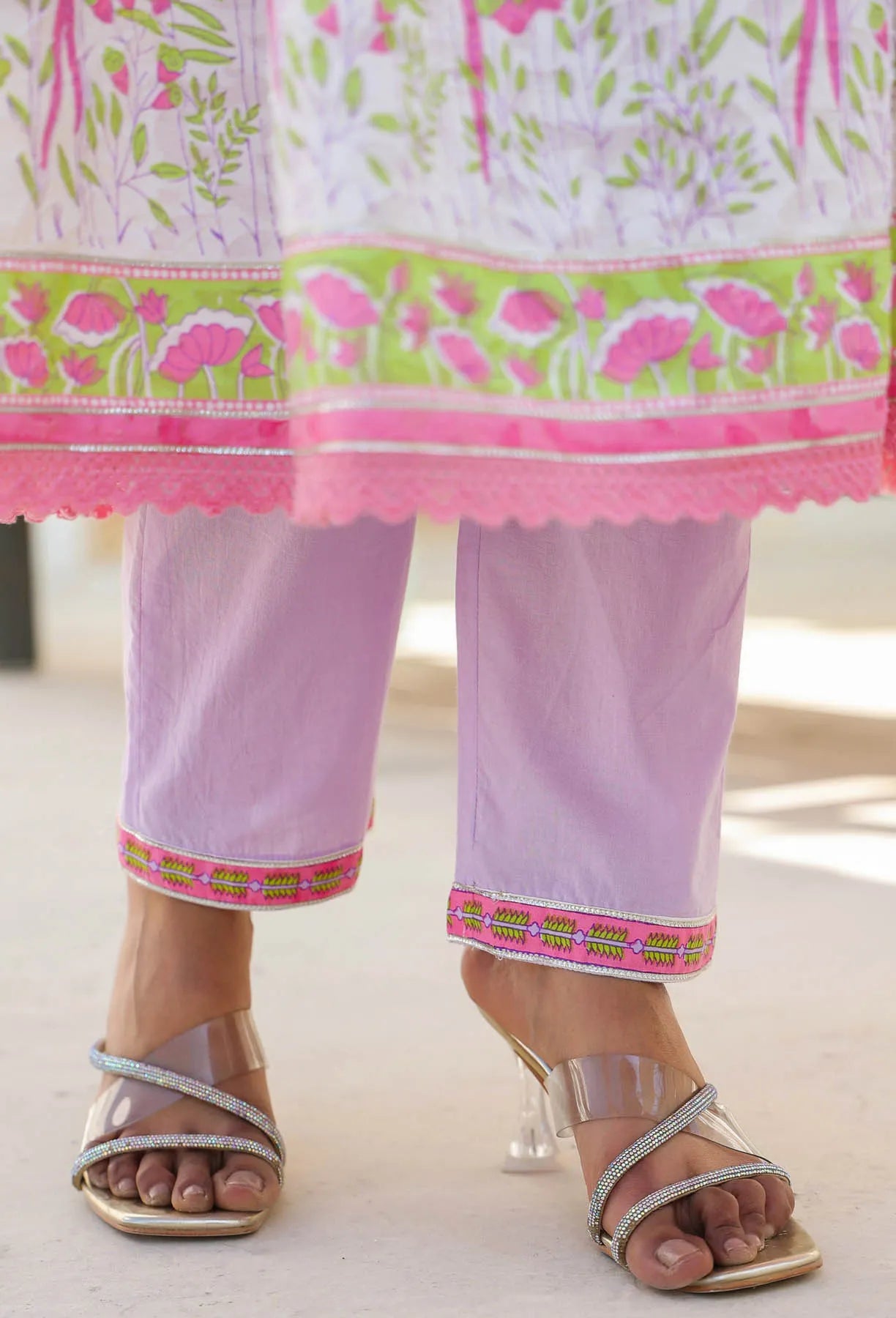 Person wearing a light purple outfit with pink and green floral patterns on a white background