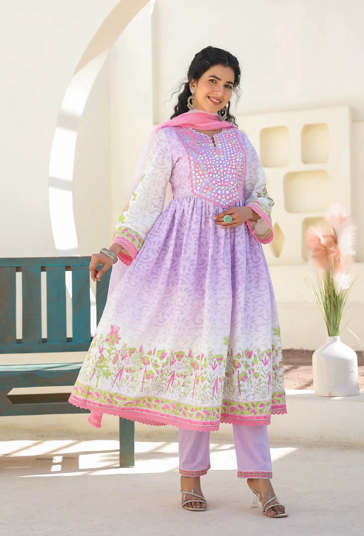 Woman wearing a light purple and pink traditional outfit with floral patterns indoors.