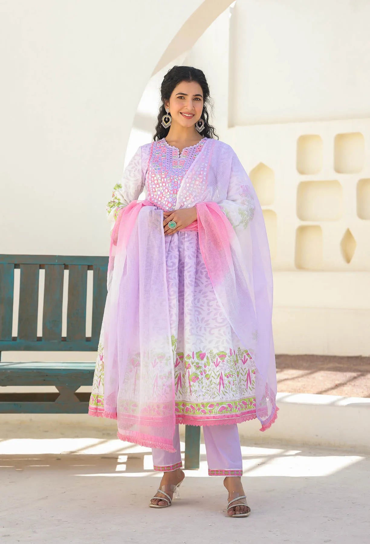 Woman wearing a traditional outfit with a pink and white dupatta in a bright setting