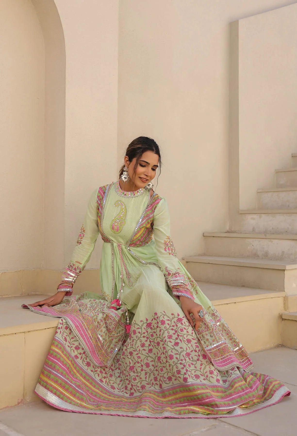 Woman in a traditional outfit sitting on a staircase in an elegant interior setting
