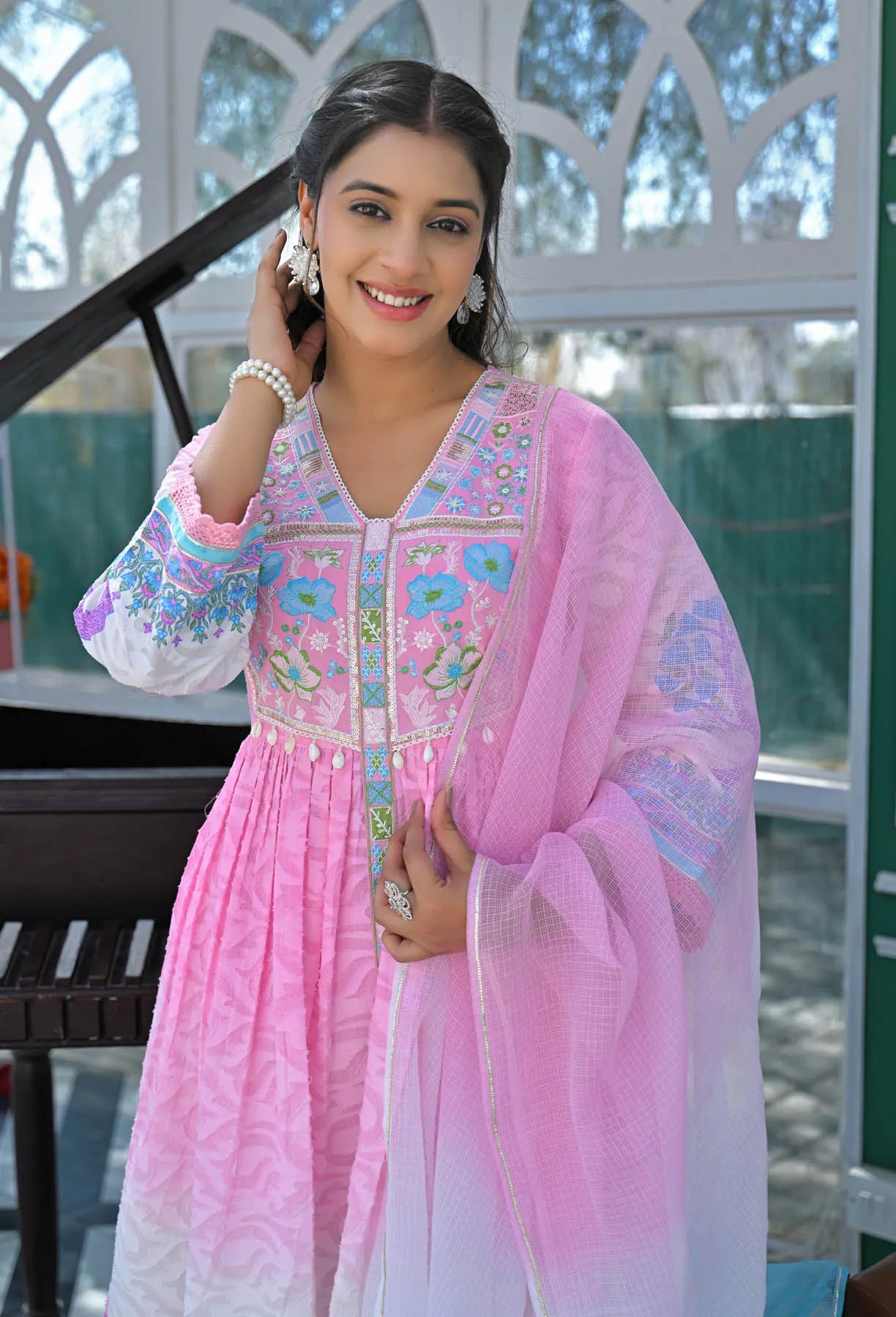 Woman wearing a pink embroidered traditional outfit outdoors.