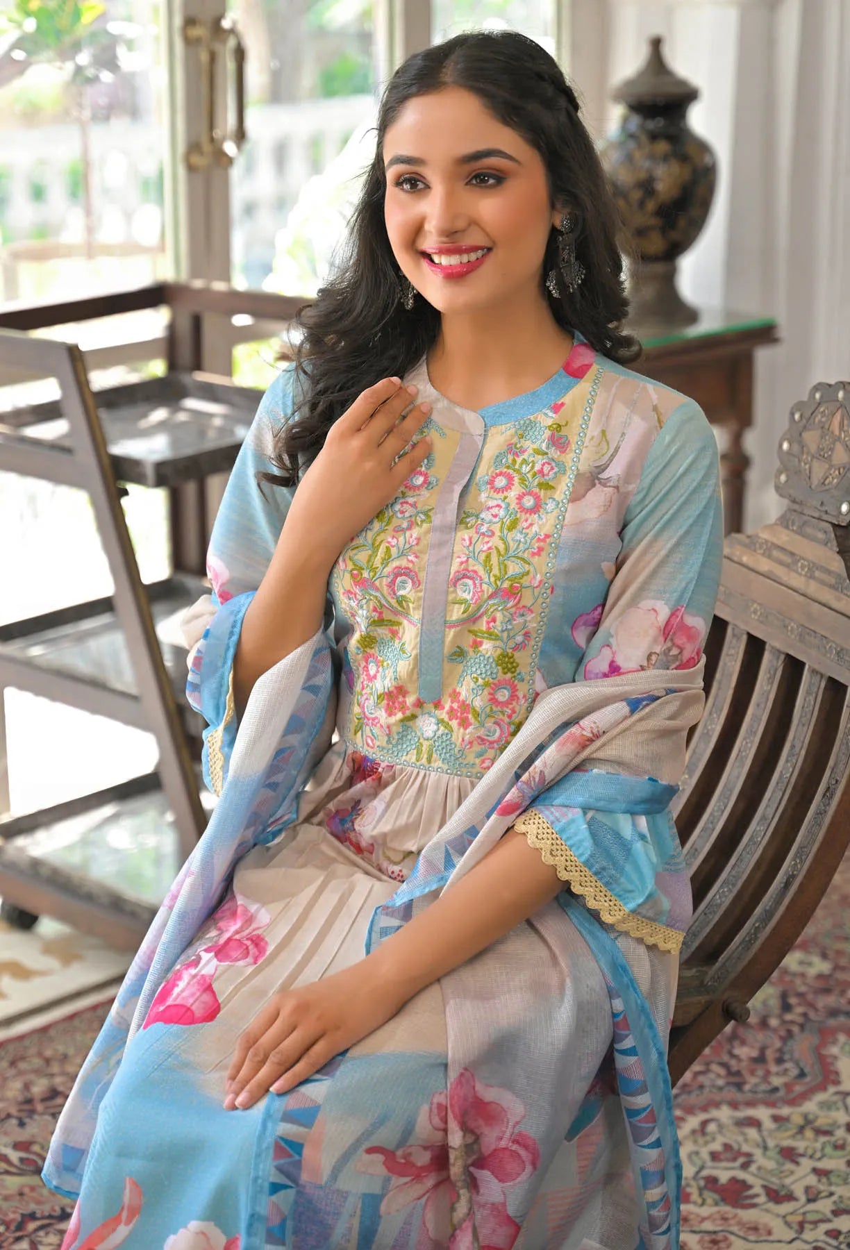Woman in a floral dress sitting on a wooden chair indoors