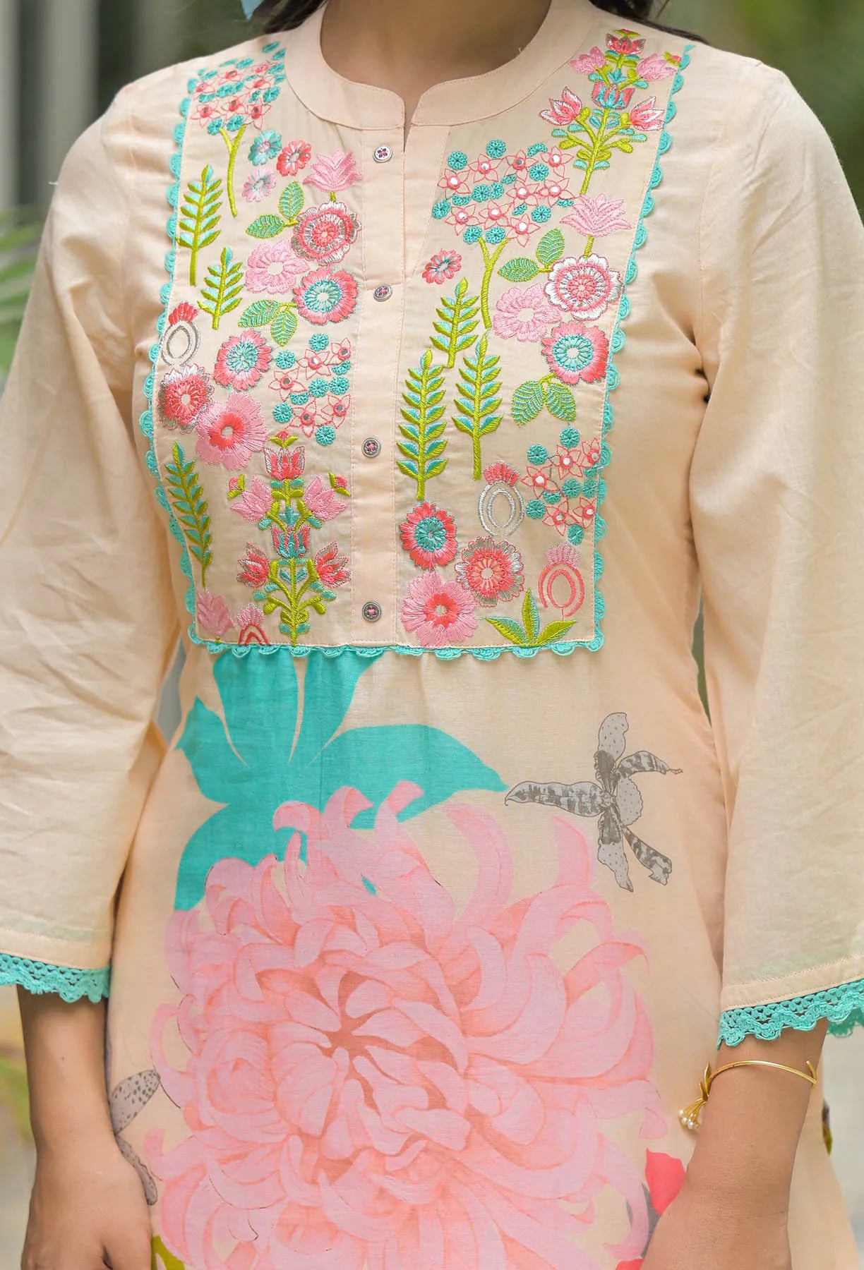 Beige kurta with floral embroidery and pink floral design on a blurred background