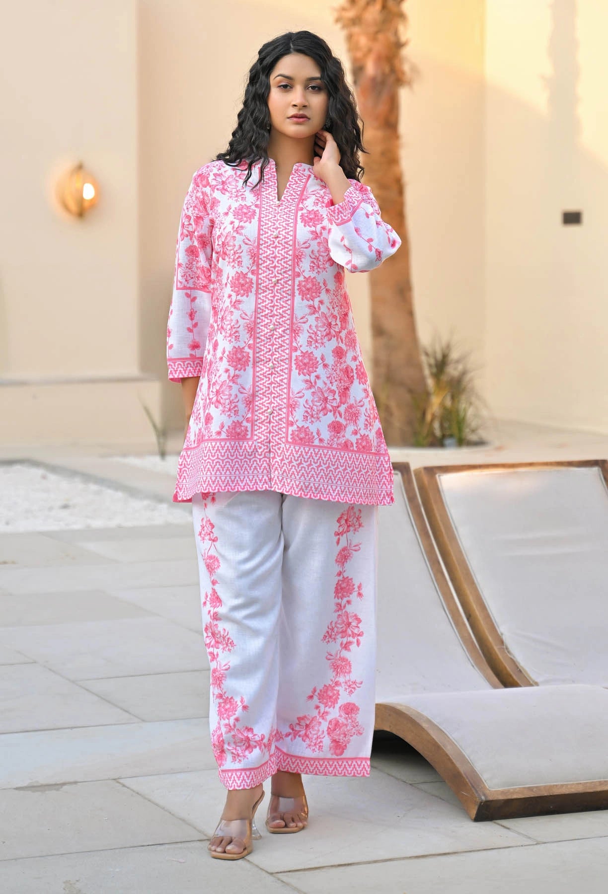 Woman wearing a pink and white embroidered outfit standing outdoors.