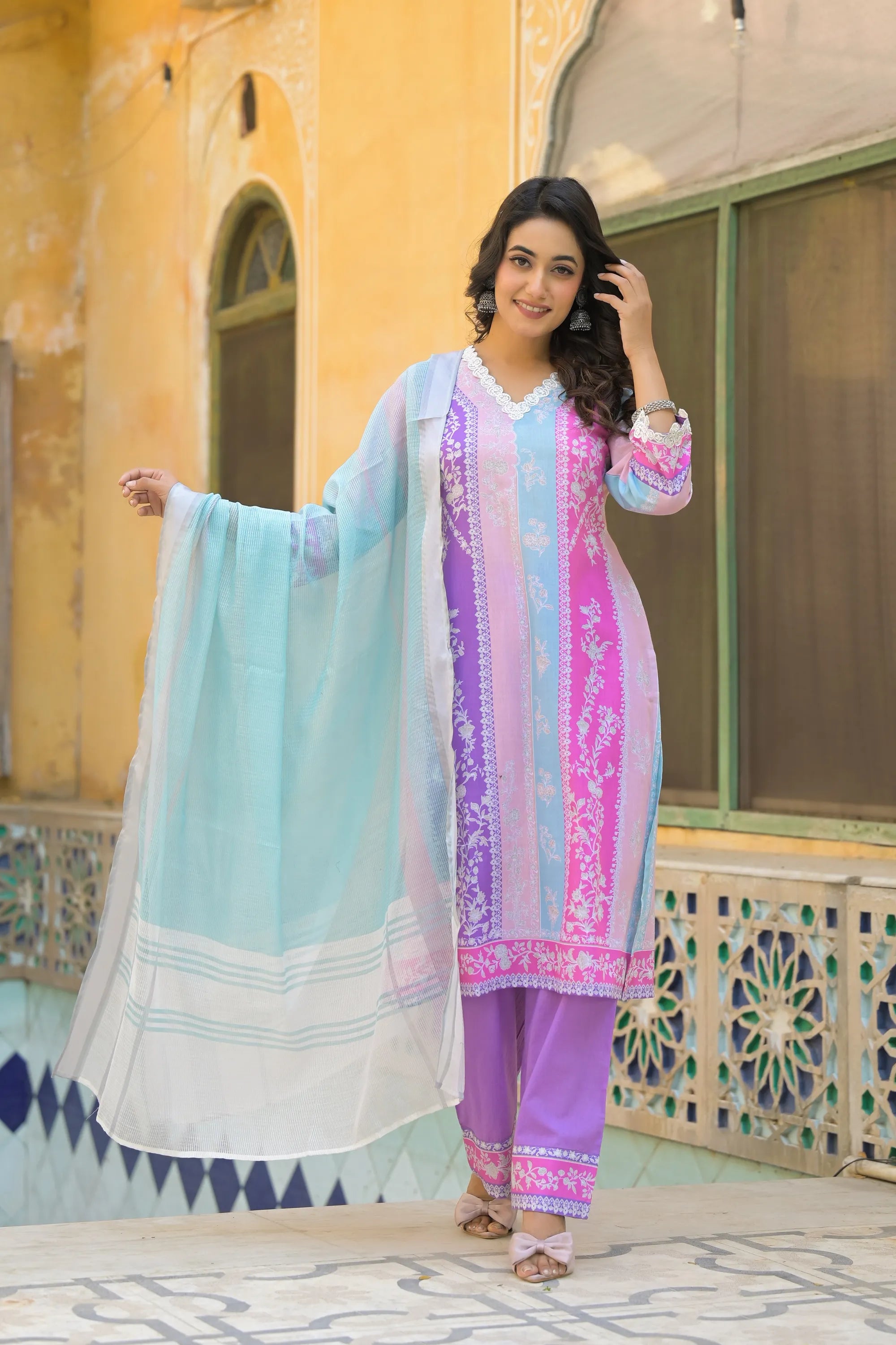 Woman in a colorful traditional outfit standing in front of a decorative building.