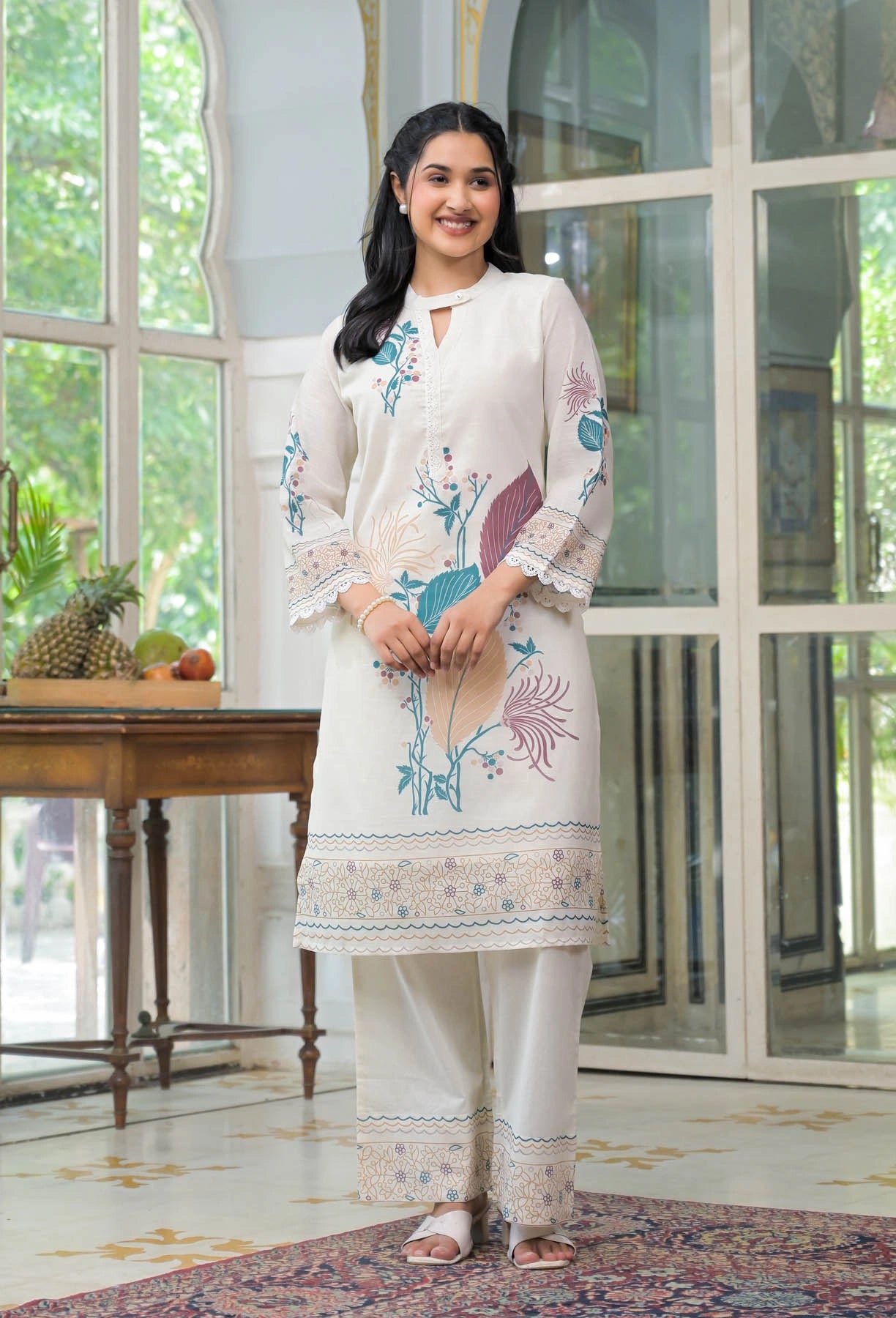 Woman wearing a white embroidered kurta with palazzo pants in a well-lit room.