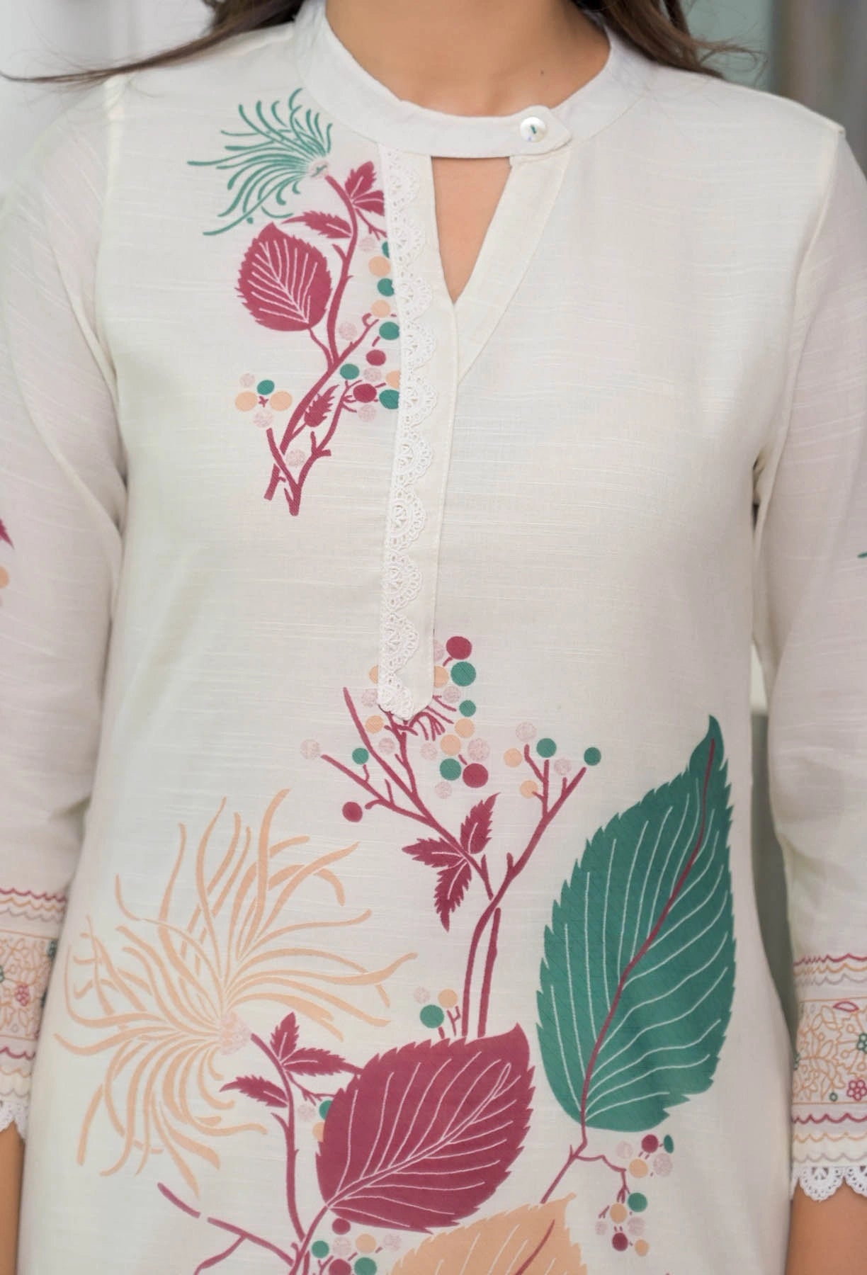 White embroidered dress with colorful floral patterns on a blurred background