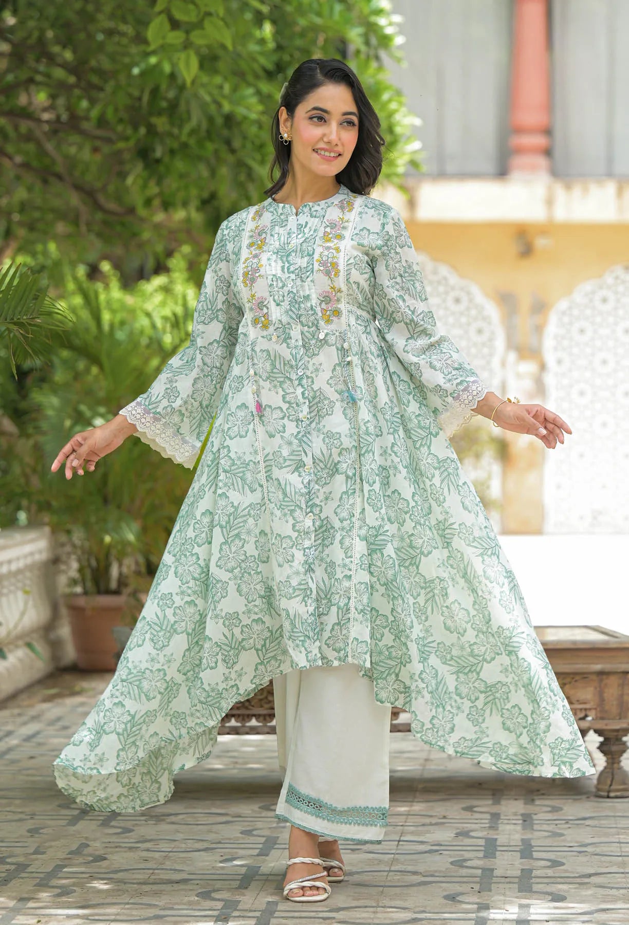 Woman wearing a light green floral kurta with white pants in an outdoor setting.