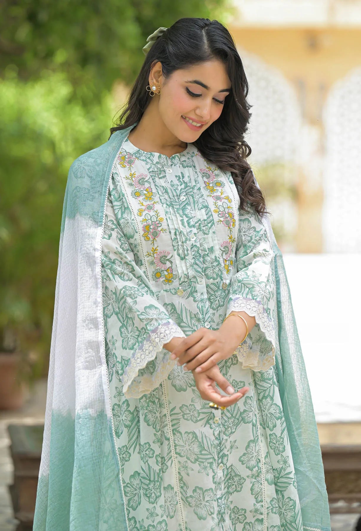 Woman wearing a light green and white floral traditional outfit with a dupatta.