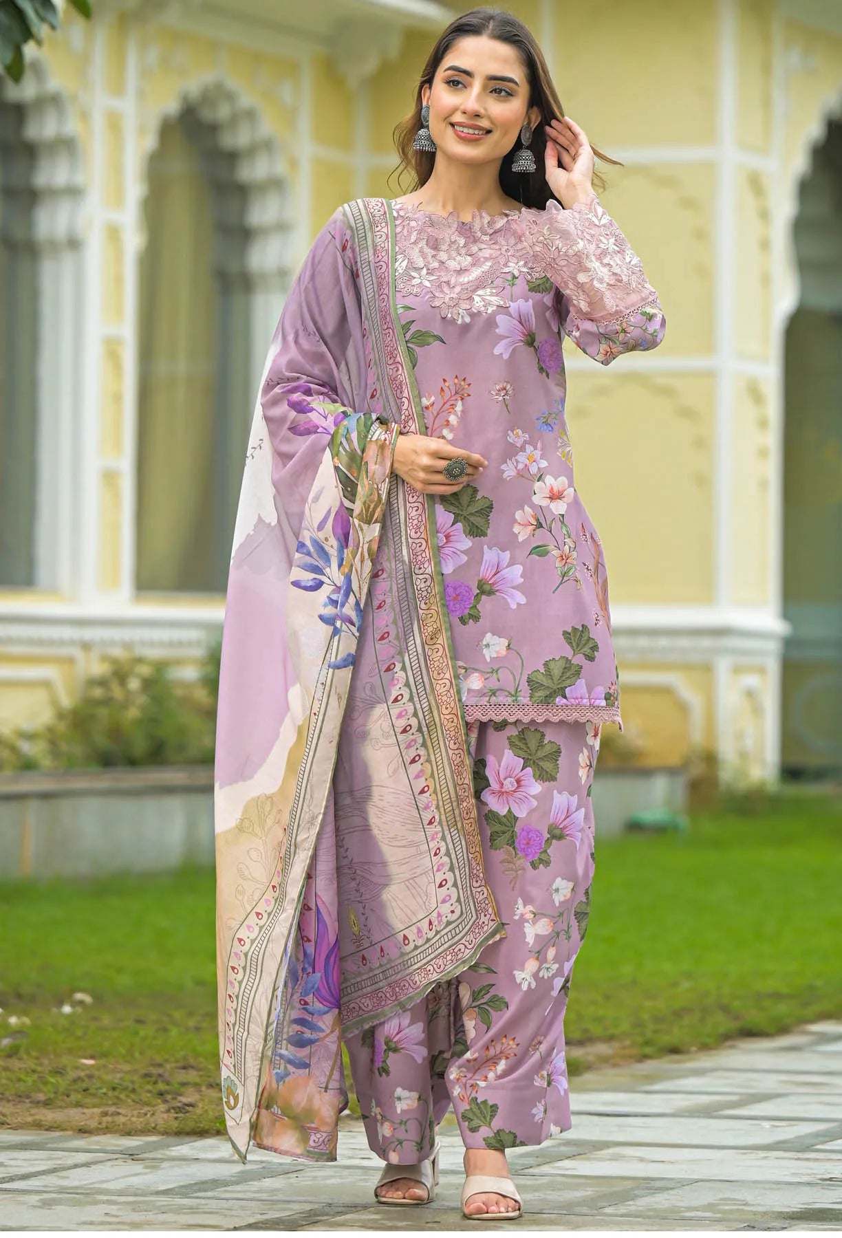 Woman in a traditional outfit with floral patterns standing in front of a building.