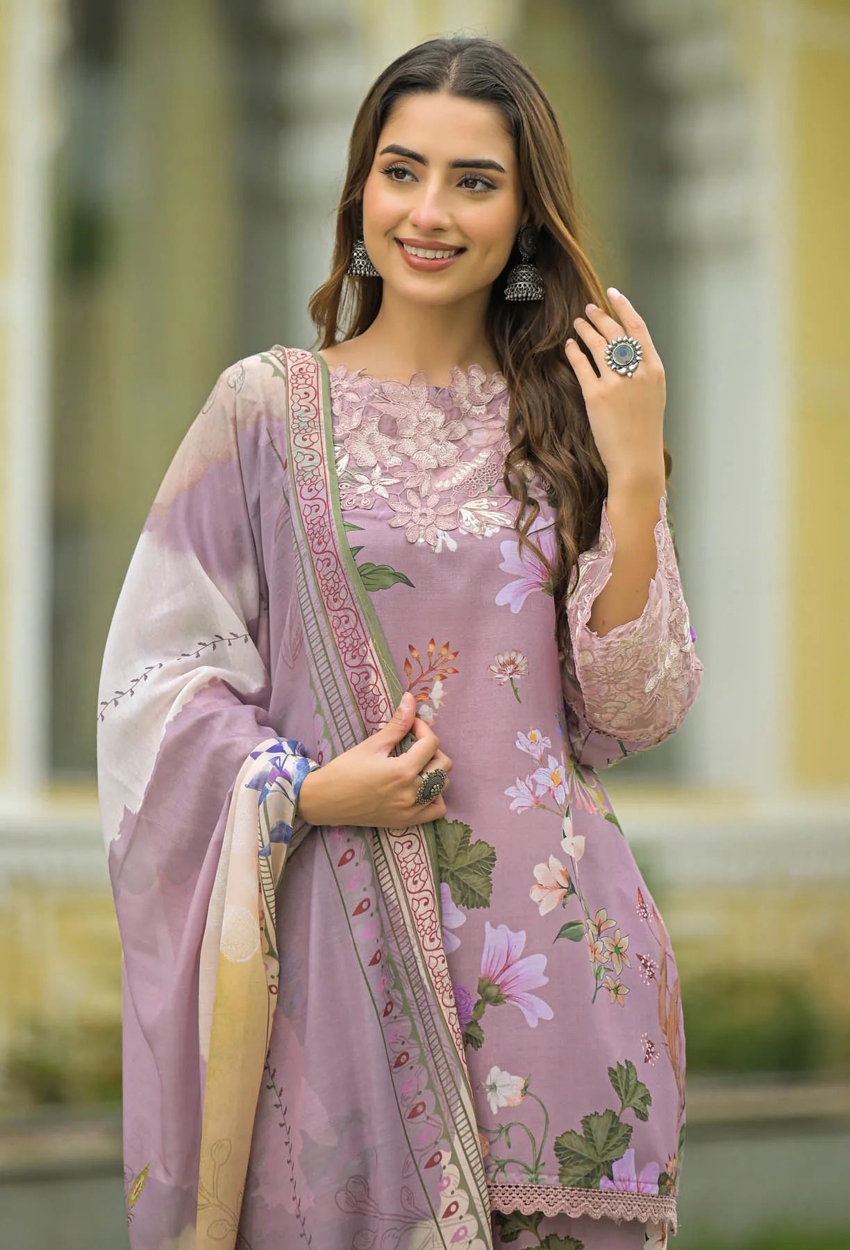 Woman wearing a floral embroidered pink and white traditional outfit with a matching dupatta.