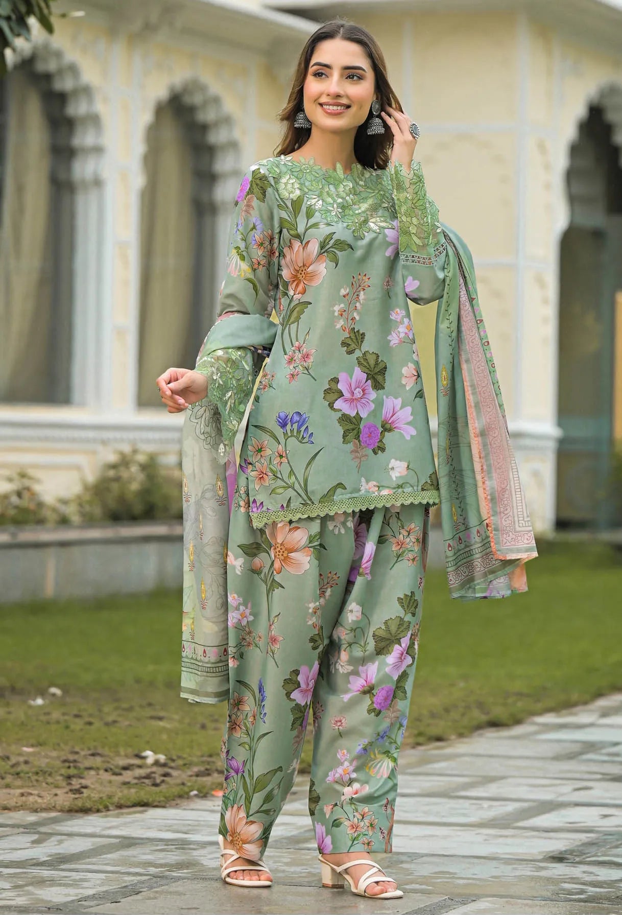 Woman wearing a green floral outfit standing outdoors.