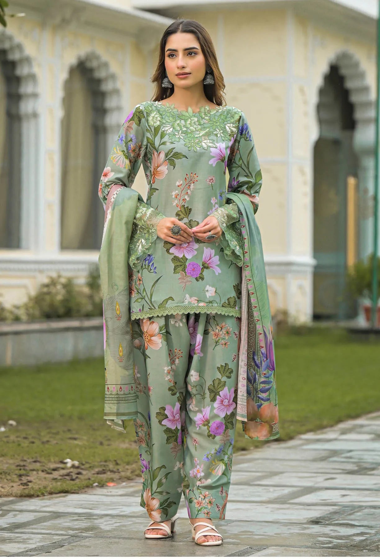 Woman wearing a green floral outfit standing outdoors.